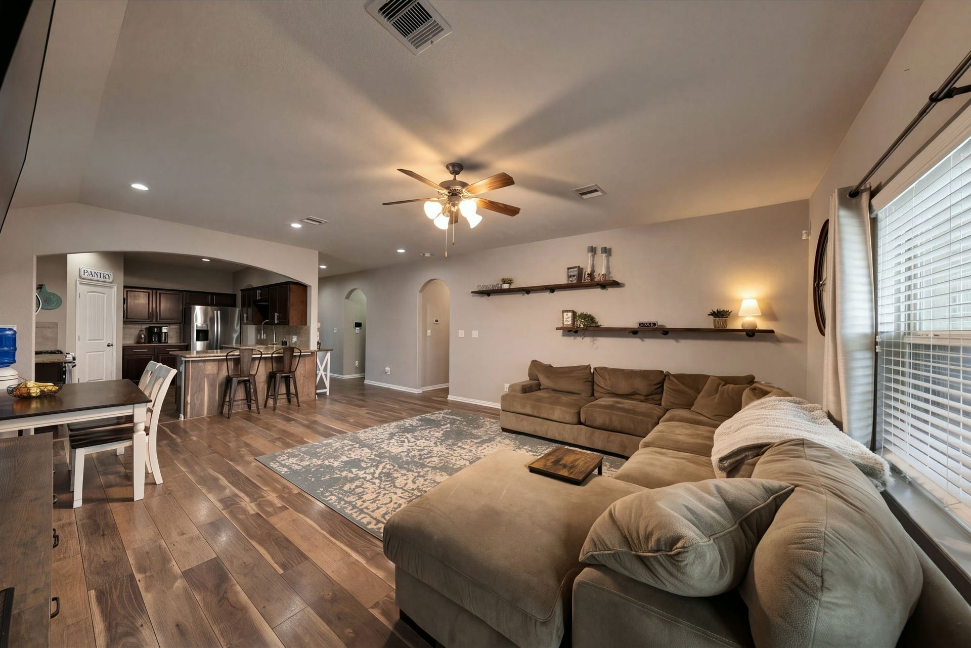336 Country Crossing Circle, Magnolia, TX 77354 Spacious open-concept living area with warm wood flooring, a convenient breakfast bar. Natural light filters in through large windows, creating an inviting atmosphere.