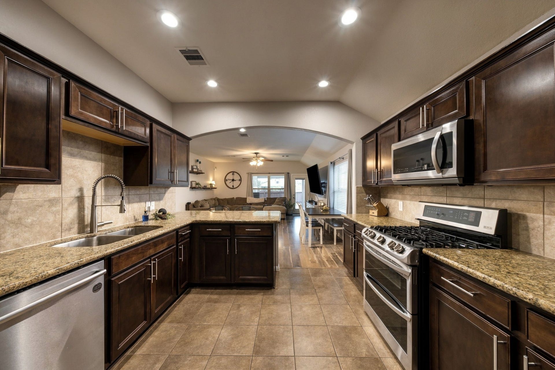 336 Country Crossing Circle, Magnolia, TX 77354 Spacious kitchen with rich dark wood cabinetry, granite countertops, modern stainless steel appliances, and a seamless flow into the inviting living area.