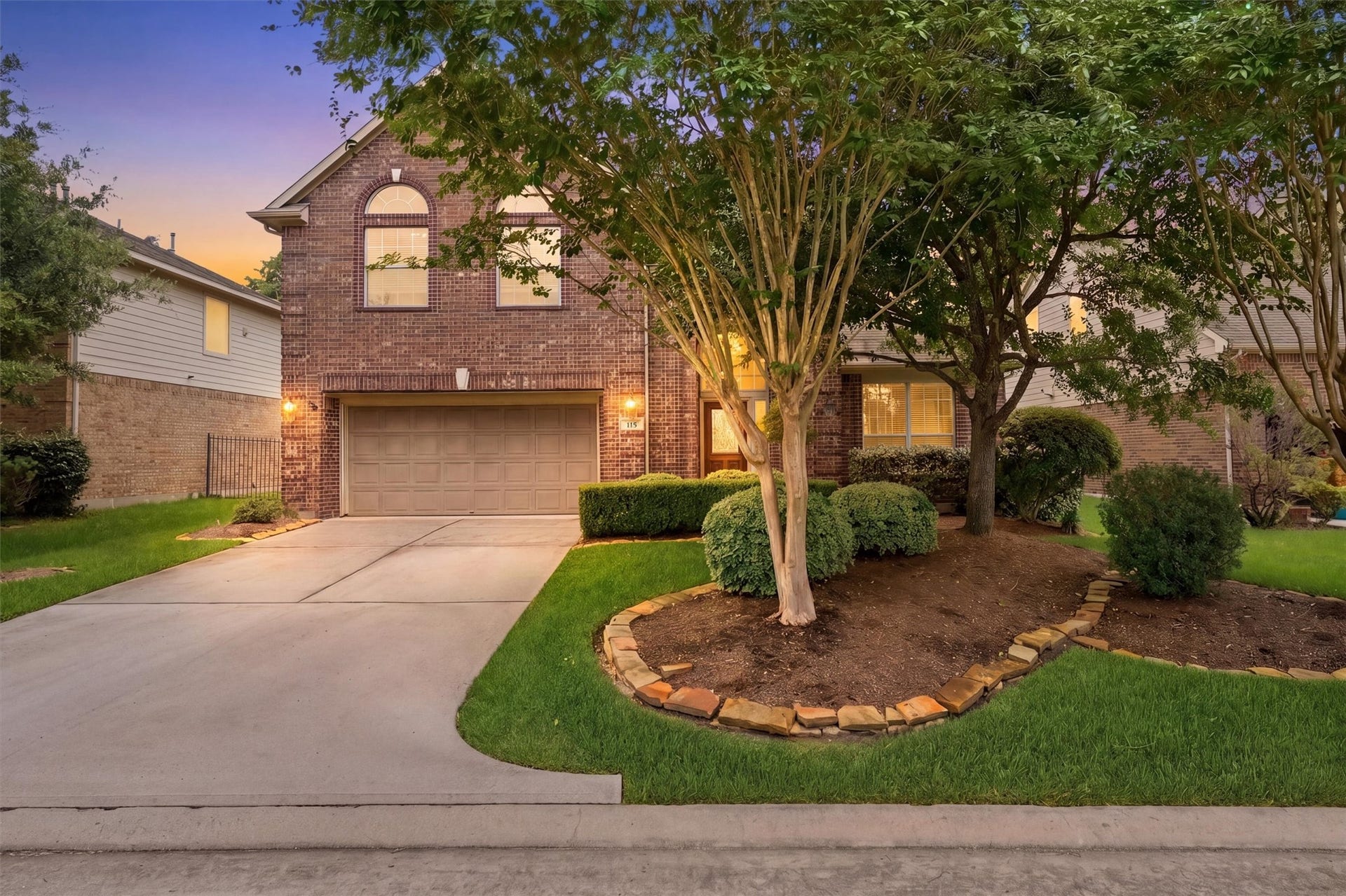 This backyard features a spacious patio with comfortable seating, a lush green lawn, and a beautiful pool with a stone waterfall, all enclosed by a wooden fence for privacy.