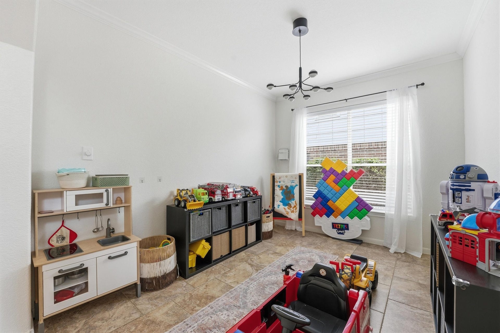 Bright and airy room with a large window, carpeted floor, ceiling fan, built-in shelving, and space for a desk and keyboard. Ideal as a home office or music room.