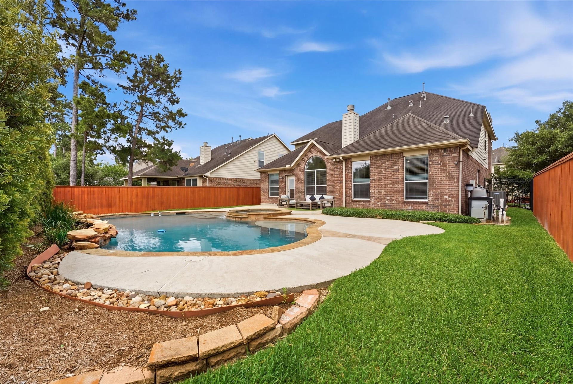 Charming two-story brick home with a well-maintained front yard, featuring mature trees and landscaping. The property includes a spacious driveway leading to a two-car garage, creating a welcoming curb appeal in a serene neighborhood setting.