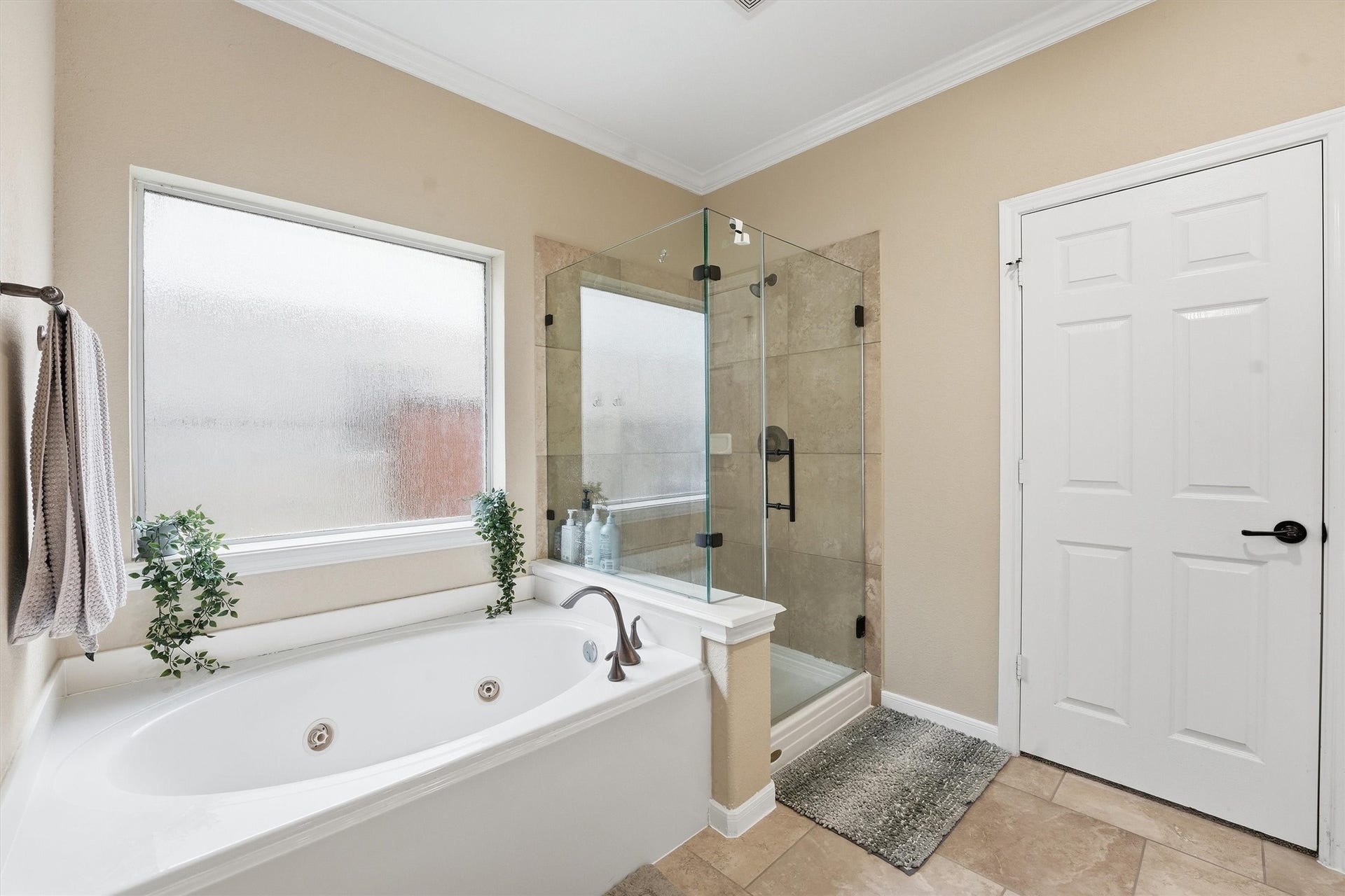 This bathroom features a spacious double vanity with a sleek black countertop and large mirror. It has modern lighting fixtures, neutral tile flooring, and white cabinetry, creating a clean and elegant look.