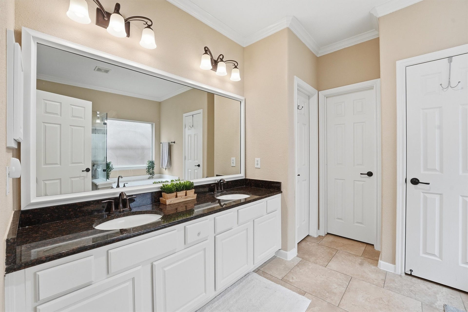 This spacious bedroom features a neutral color palette and large windows that allow natural light to fill the room. It includes a ceiling fan, plush carpeting, and stylish furnishings, creating a cozy and inviting atmosphere.