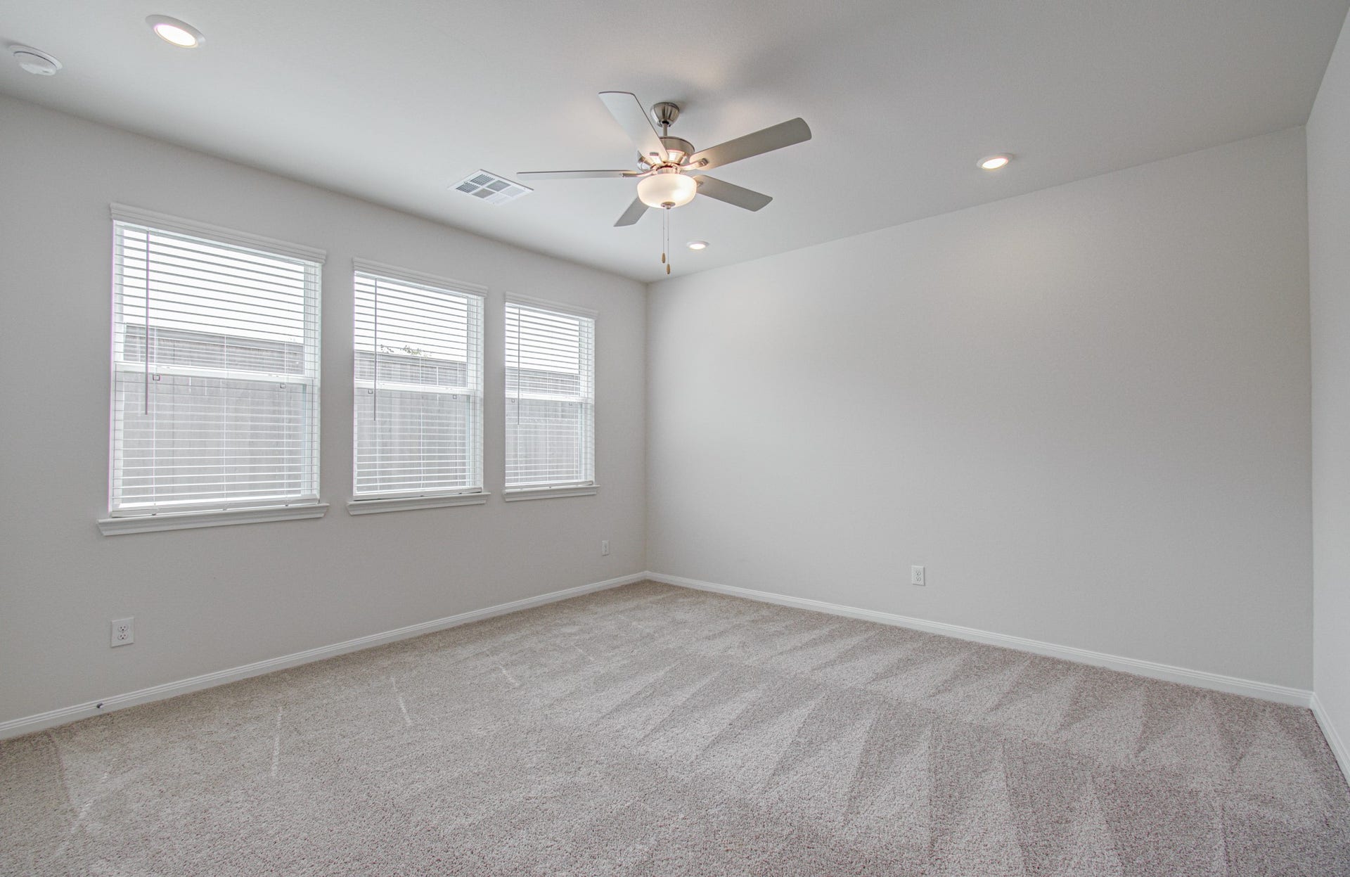 14210 Aston Pine Drive, Houston, TX 77032 Bright and spacious game-room featuring a ceiling fan, plush carpet, and ample natural light from three large windows. Please Note this is a different home/floorplan in the community.