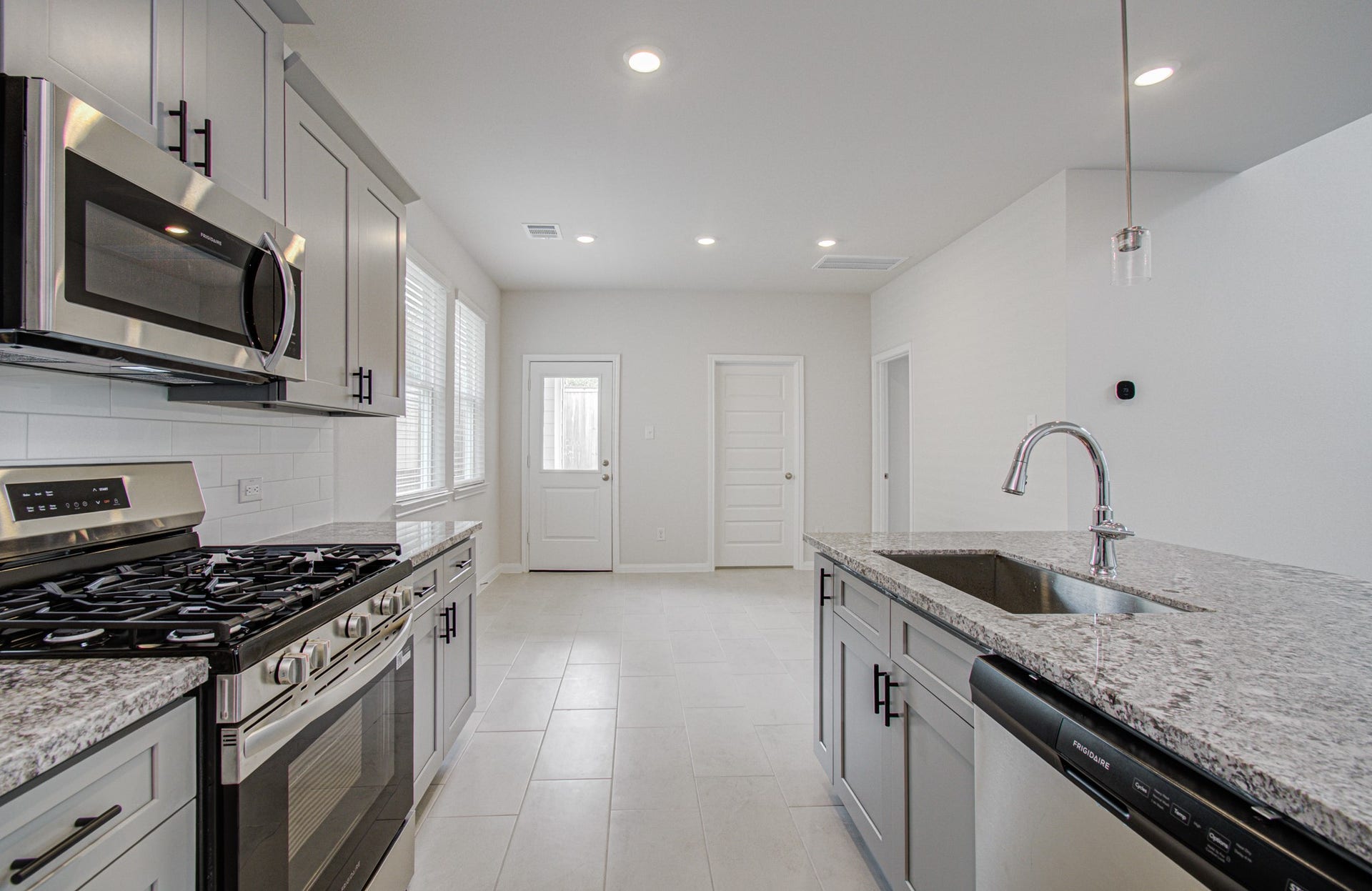 14210 Aston Pine Drive, Houston, TX 77032 Modern kitchen with sleek stainless steel appliances, granite countertops, and ample natural light, offering a bright and inviting space for cooking and entertaining. Please Note this is a different home/floorplan in the community.