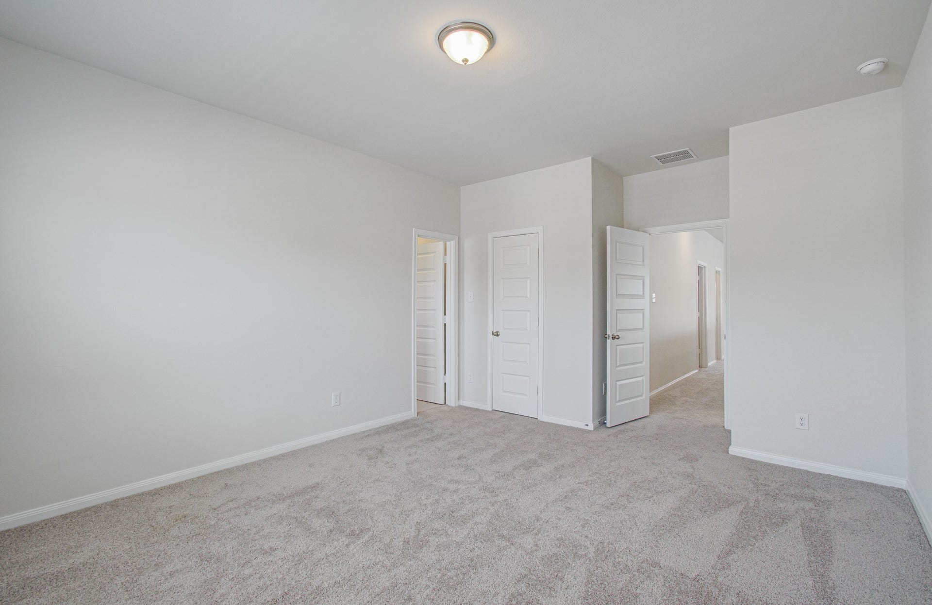14210 Aston Pine Drive, Houston, TX 77032 Spacious secondary suite bedroom with plush carpeting, soft neutral walls, and ample natural light, featuring dual door . Please Note this is a different home/floorplan in the community.