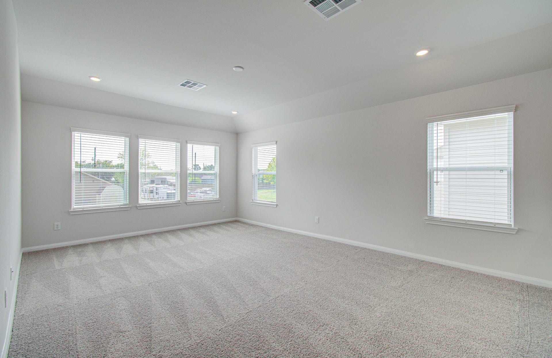 14210 Aston Pine Drive, Houston, TX 77032 Spacious and bright room with large windows, soft carpeting, and recessed lighting, offering a comfortable and inviting living area. Please Note this is a different home/floorplan in the community.