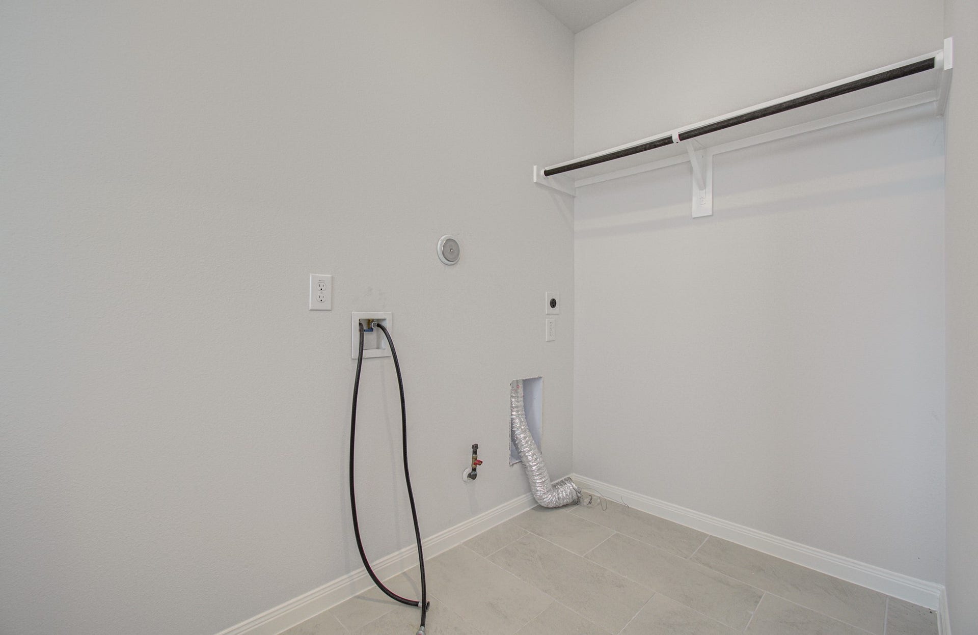 14210 Aston Pine Drive, Houston, TX 77032 Spacious laundry room featuring washer and dryer hookups, a convenient utility shelf, and tiled flooring for easy maintenance. Please Note this is a different home/floorplan in the community.