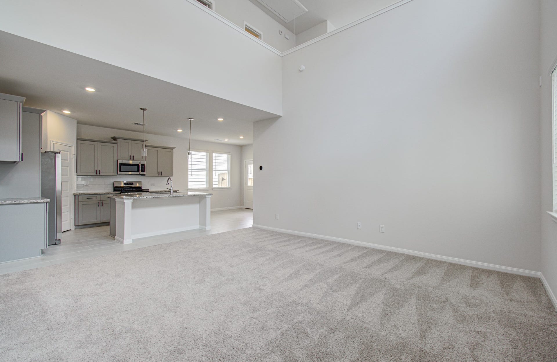 14210 Aston Pine Drive, Houston, TX 77032 Spacious living area with high ceilings and an open layout, leading to a modern kitchen featuring stainless steel appliances and a large island. Please Note this is a different home/floorplan in the community.