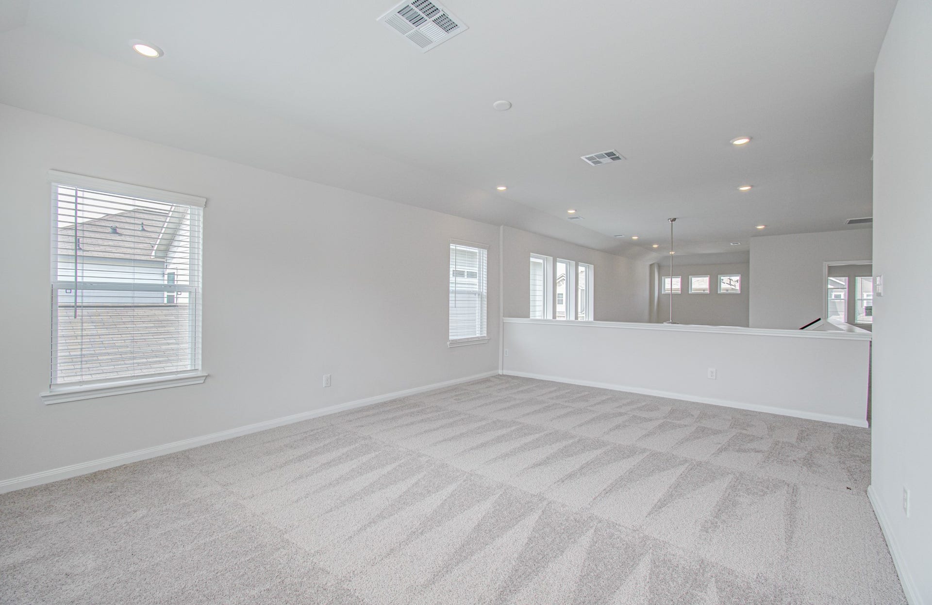 14210 Aston Pine Drive, Houston, TX 77032 Spacious and bright open-concept game-room loft area with plush carpeting, ample natural light from multiple windows, and recessed lighting for a modern touch. Please Note this is a different home/floorplan in the community.