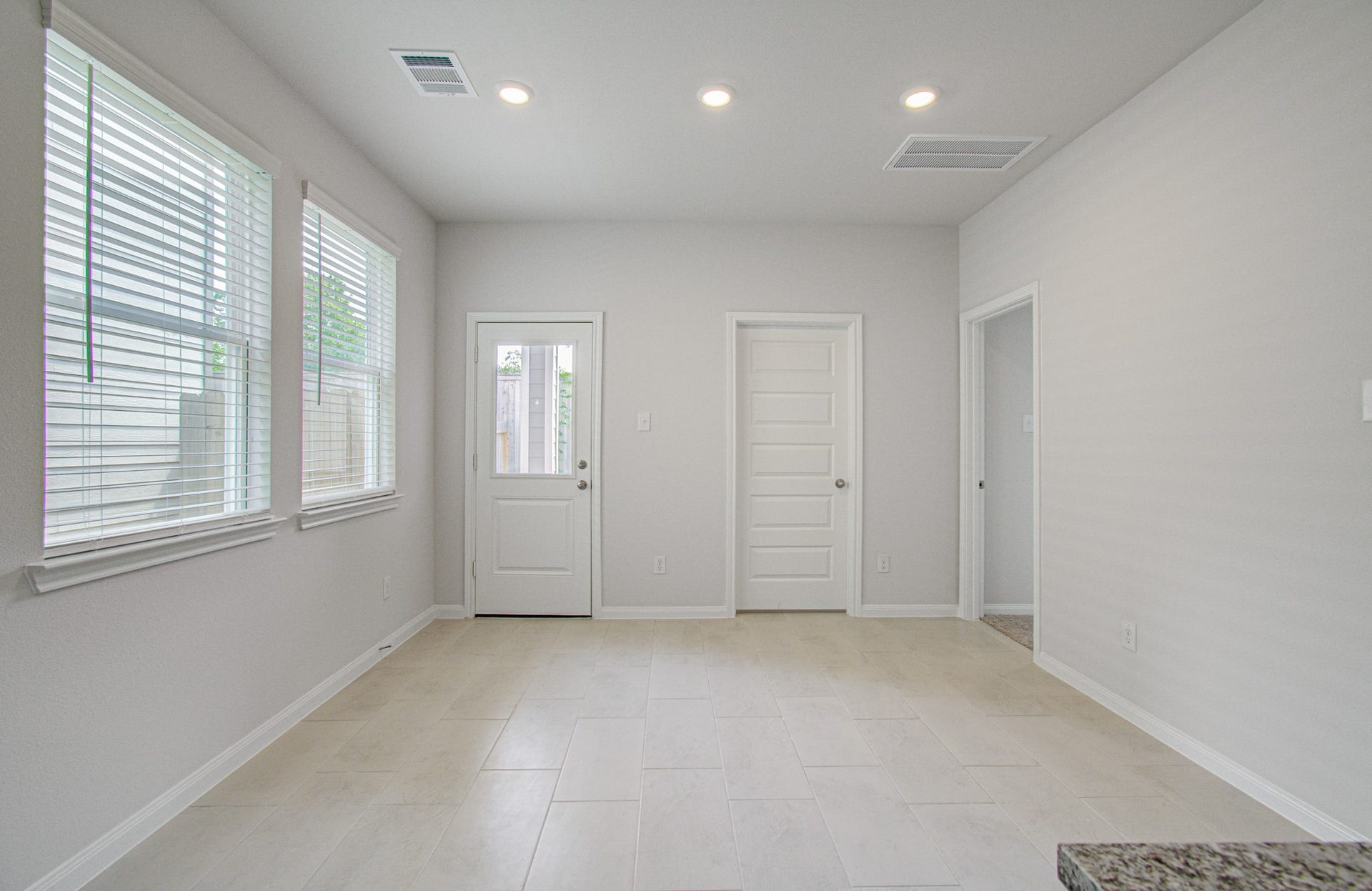 14210 Aston Pine Drive, Houston, TX 77032 Bright, airy dining area with large windows, tiled flooring, and modern recessed lighting, offering a clean and inviting space. Please Note this is a different home/floorplan in the community.