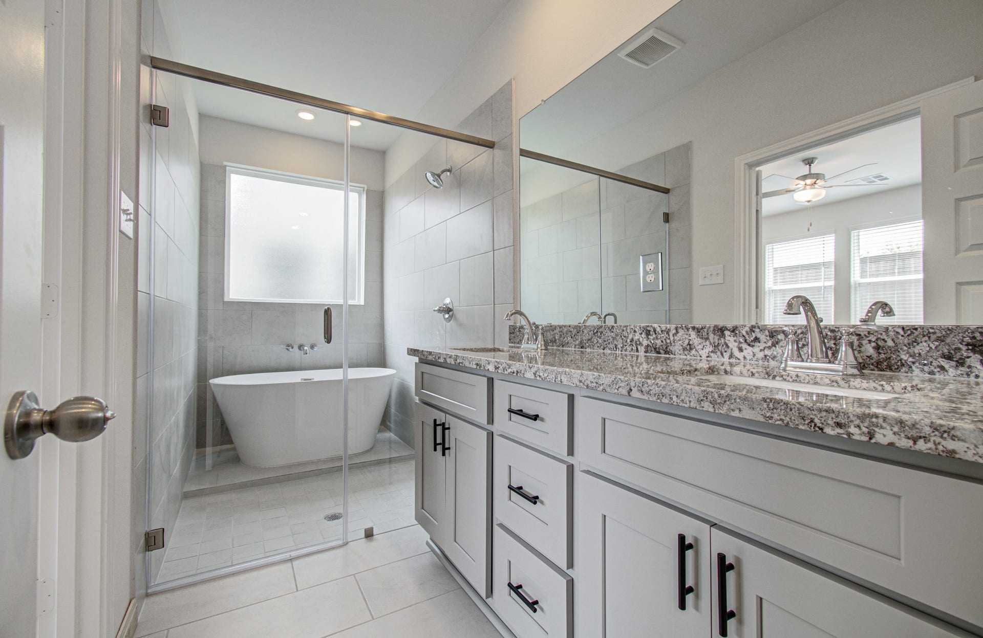 14210 Aston Pine Drive, Houston, TX 77032 Elegant primary bathroom featuring a spacious glass-enclosed shower and a luxurious soaking tub, complemented by a sleek double vanity with granite countertops. Please Note this is a different home/floorplan in the community.