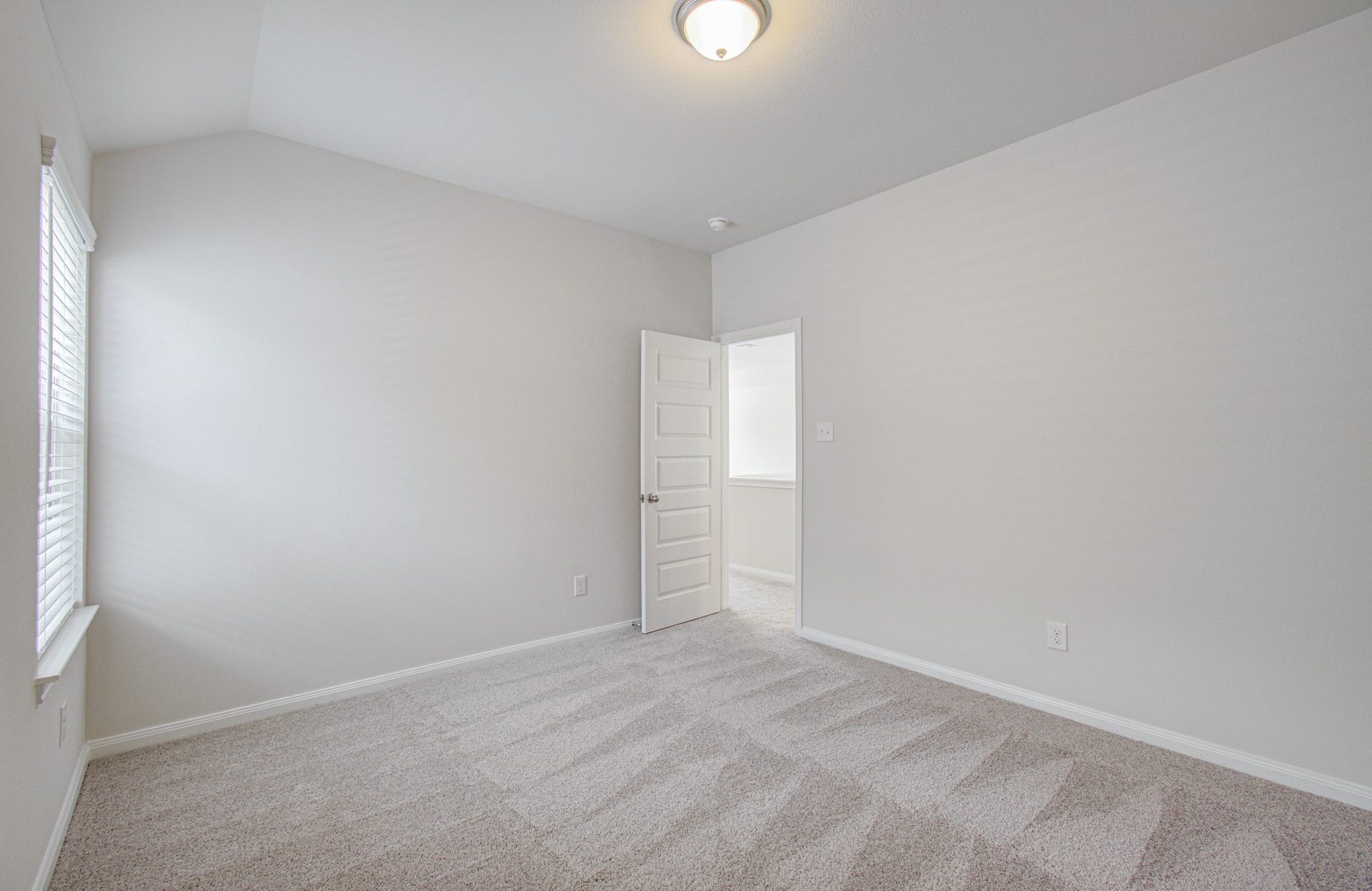 14210 Aston Pine Drive, Houston, TX 77032 Bright and inviting fourth bedroom with plush carpeting and a soft neutral color palette, featuring a large window that fills the space with natural light. Please Note this is a different home/floorplan in the community.