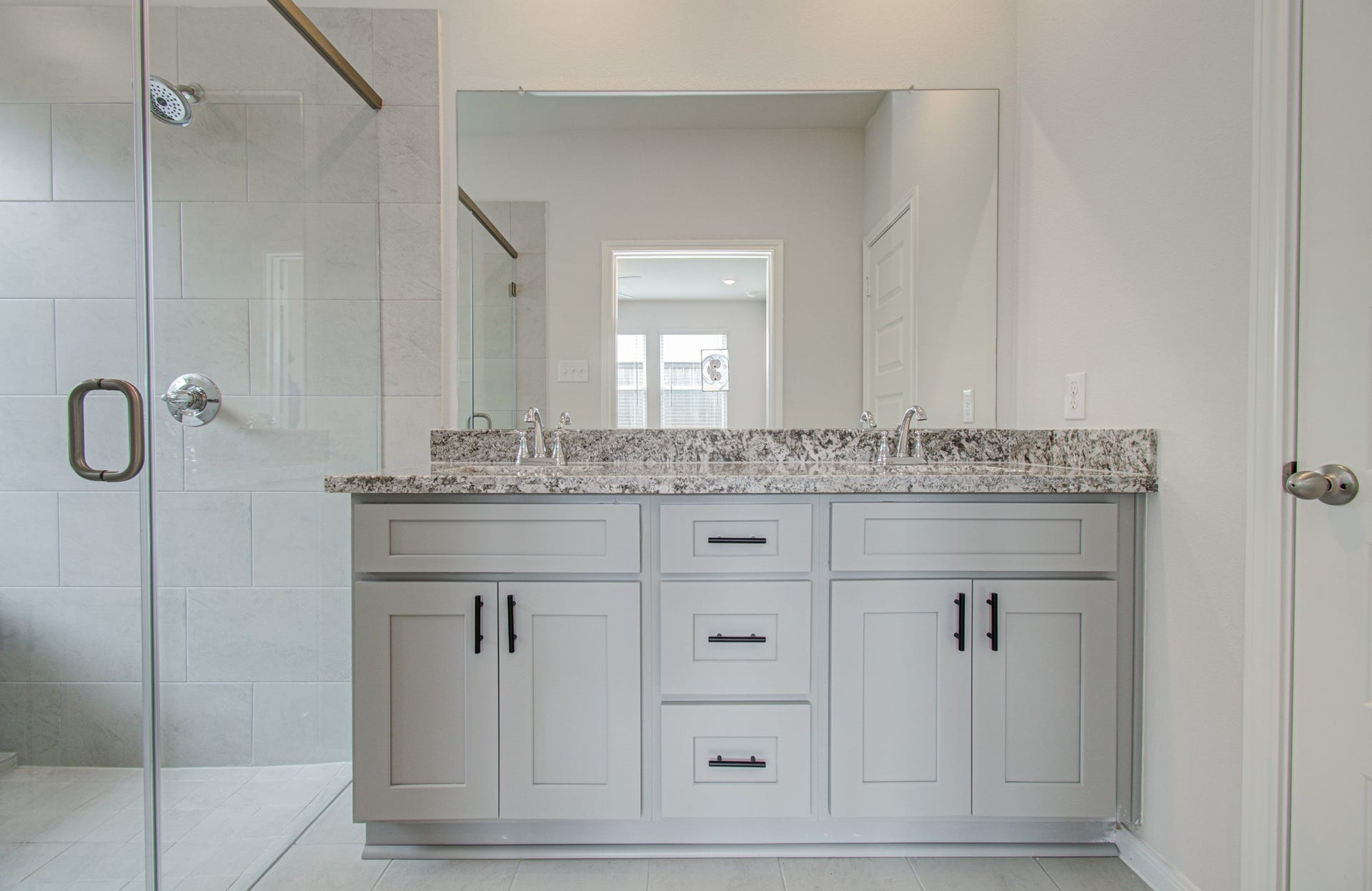 14210 Aston Pine Drive, Houston, TX 77032 Elegant primary bathroom featuring a sleek double vanity with granite countertops and a spacious glass-enclosed shower. Please Note this is a different home/floorplan in the community.