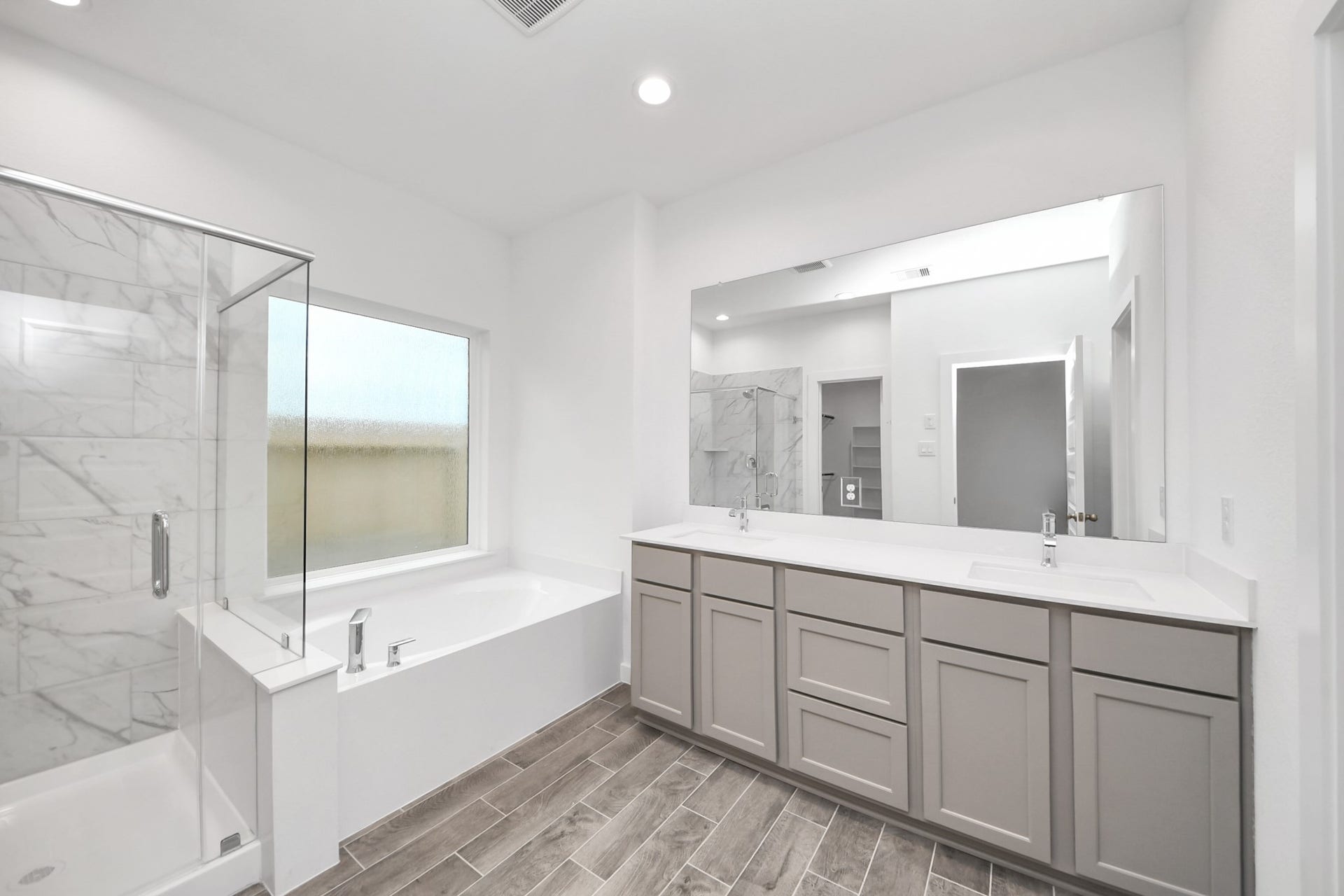 24514 Broad Park Ct, Spring, TX 77373 Escape to a spa-like oasis in this primary bathroom. Enjoy a walk-in shower with tile surround, a separate garden tub with custom detailing, and an elegant vanity featuring light countertops, modern hardware, and beautiful vanity lights. Experience luxury and relaxation in every detail.