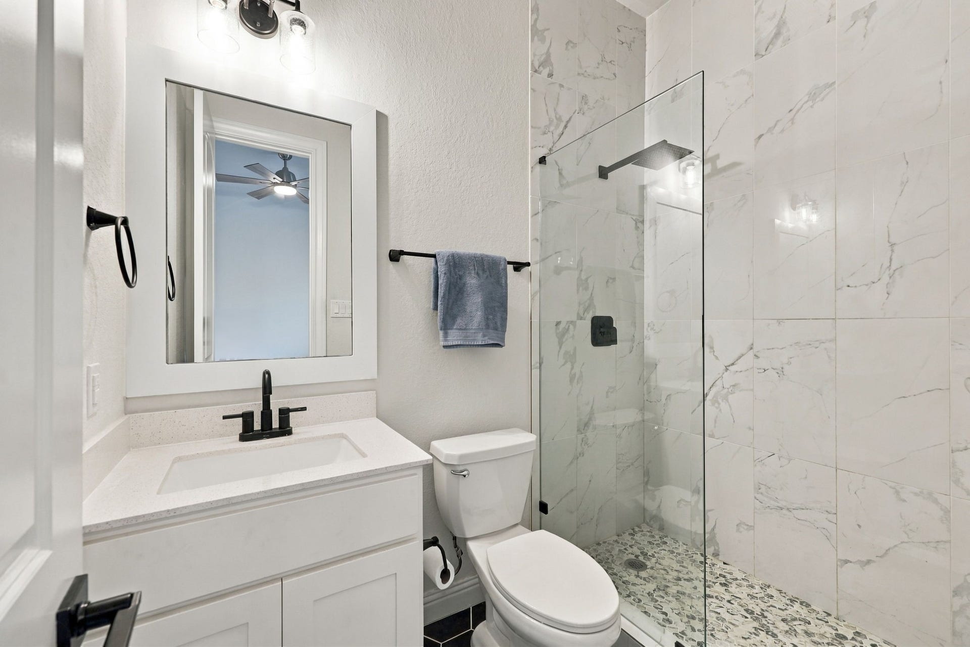 Discover another thoughtful upgrade, the secondary bathroom's original bathtub has been replaced with a  walk-in shower with floor to cieling tile features.