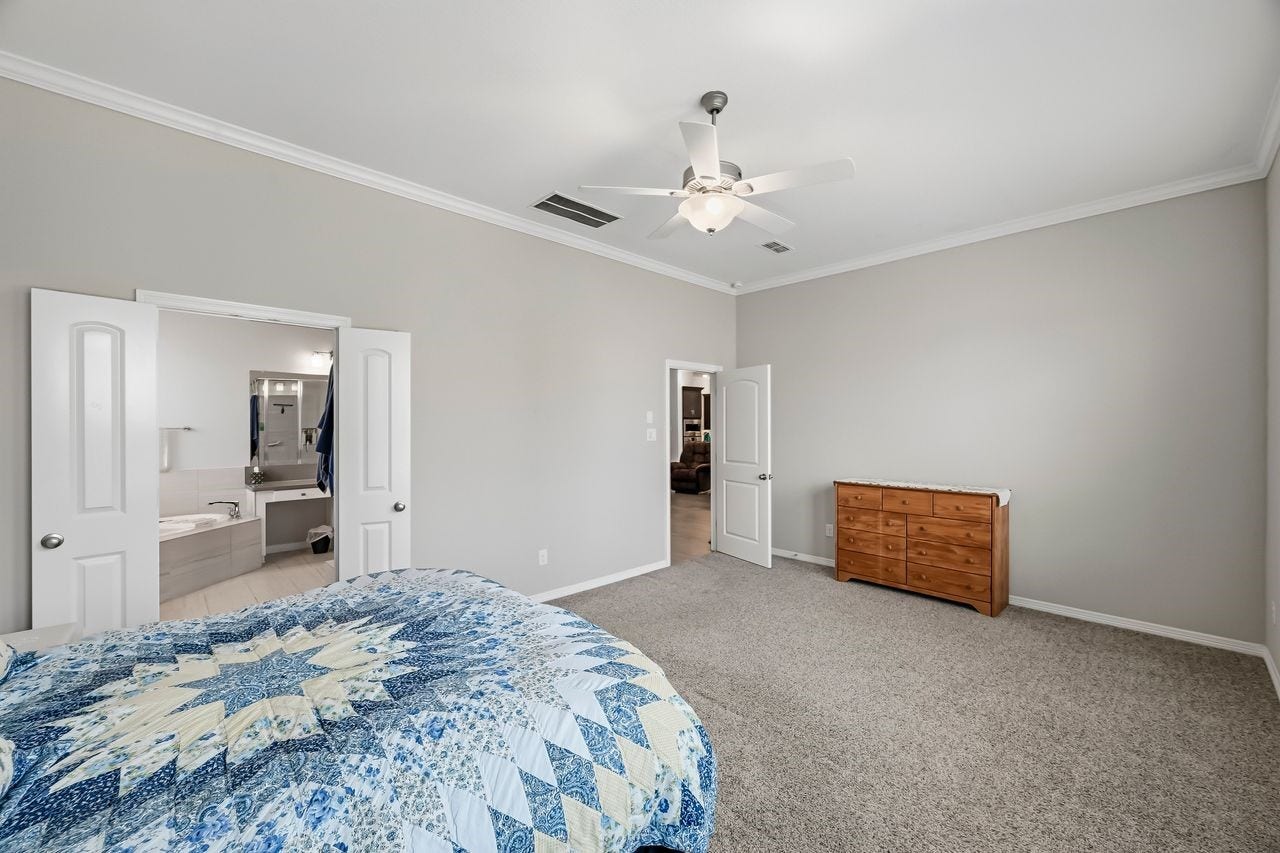 2215 Hermina Radler Drive, Richmond, TX 77469 The primary suite offers a serene escape, featuring a glimpse into the spa-like ensuite complete with a soaking tub and dual vanities.
