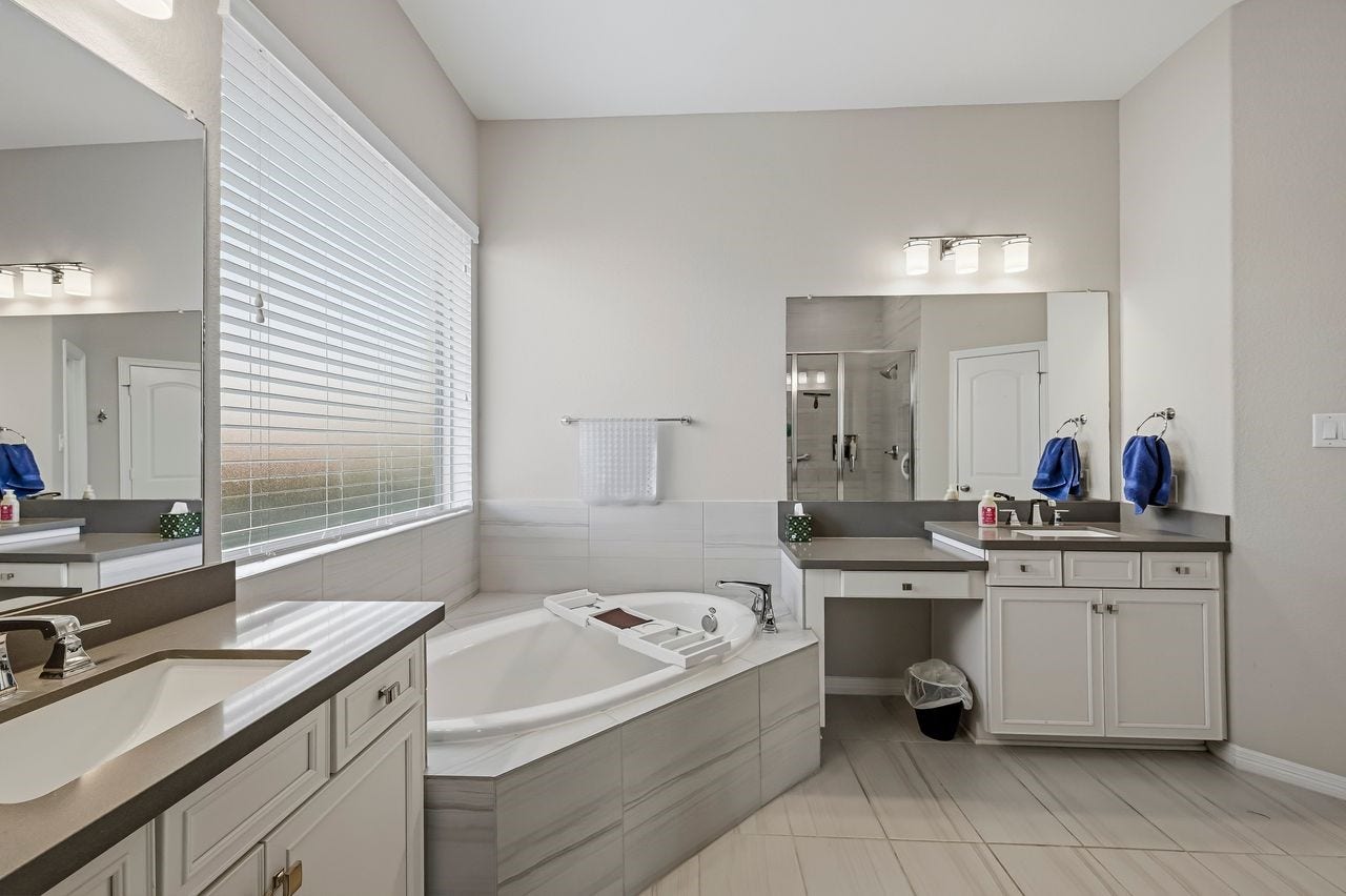 2215 Hermina Radler Drive, Richmond, TX 77469 This expansive primary ensuite offers a refined retreat, anchored by dual vanities topped with sleek quartz. The oversized mirror and a soft, neutral palette enhance the sense of light and airy sophistication.
