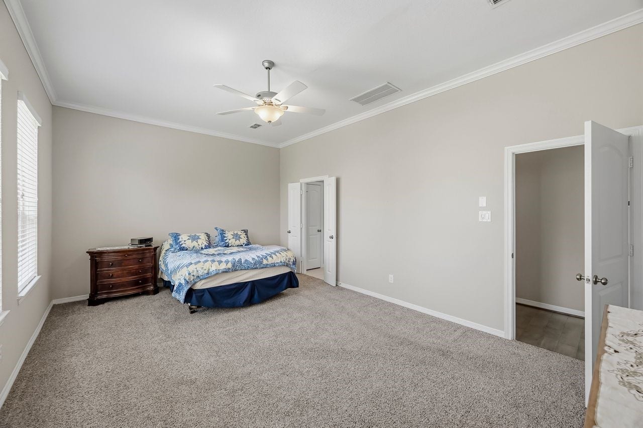 2215 Hermina Radler Drive, Richmond, TX 77469 A secondary perspective of the primary suite highlights the plush, designer carpeting and a seamless transition into the spa-like ensuite.