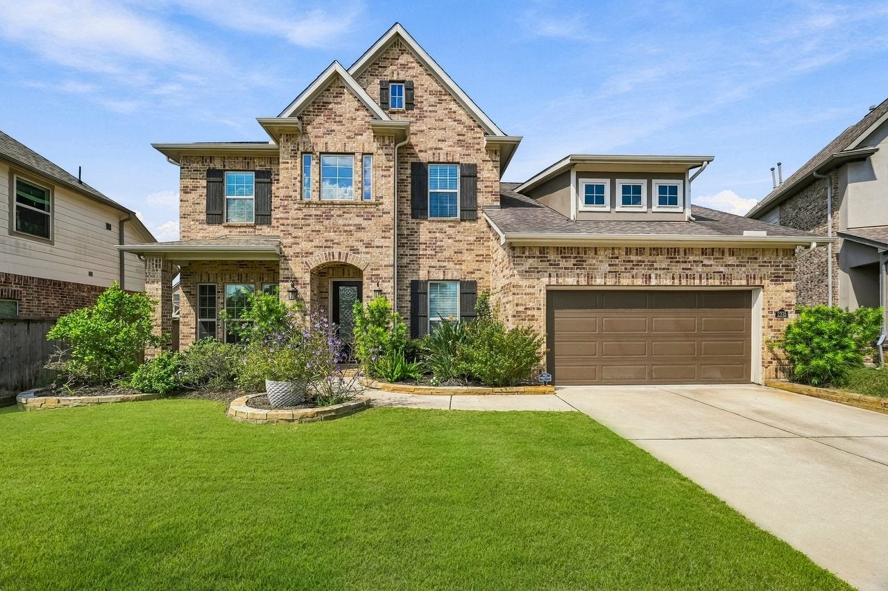 2215 Hermina Radler Drive, Richmond, TX 77469 Stately brick accents and expansive windows define this refined exterior, complemented by manicured landscaping and a lush, sprawling lawn.