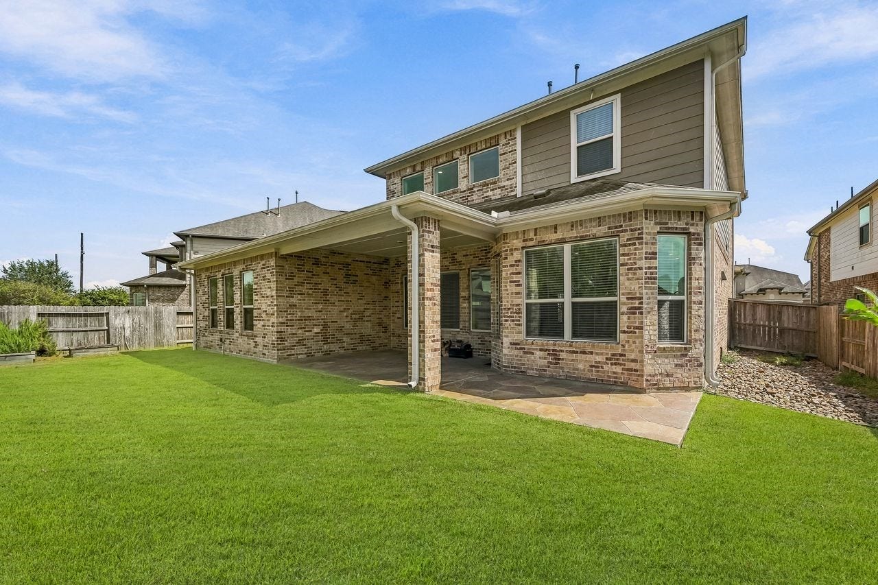 2215 Hermina Radler Drive, Richmond, TX 77469 A refined perspective of the rear exterior, highlighting the expansive proportions of the custom-tiled patio.