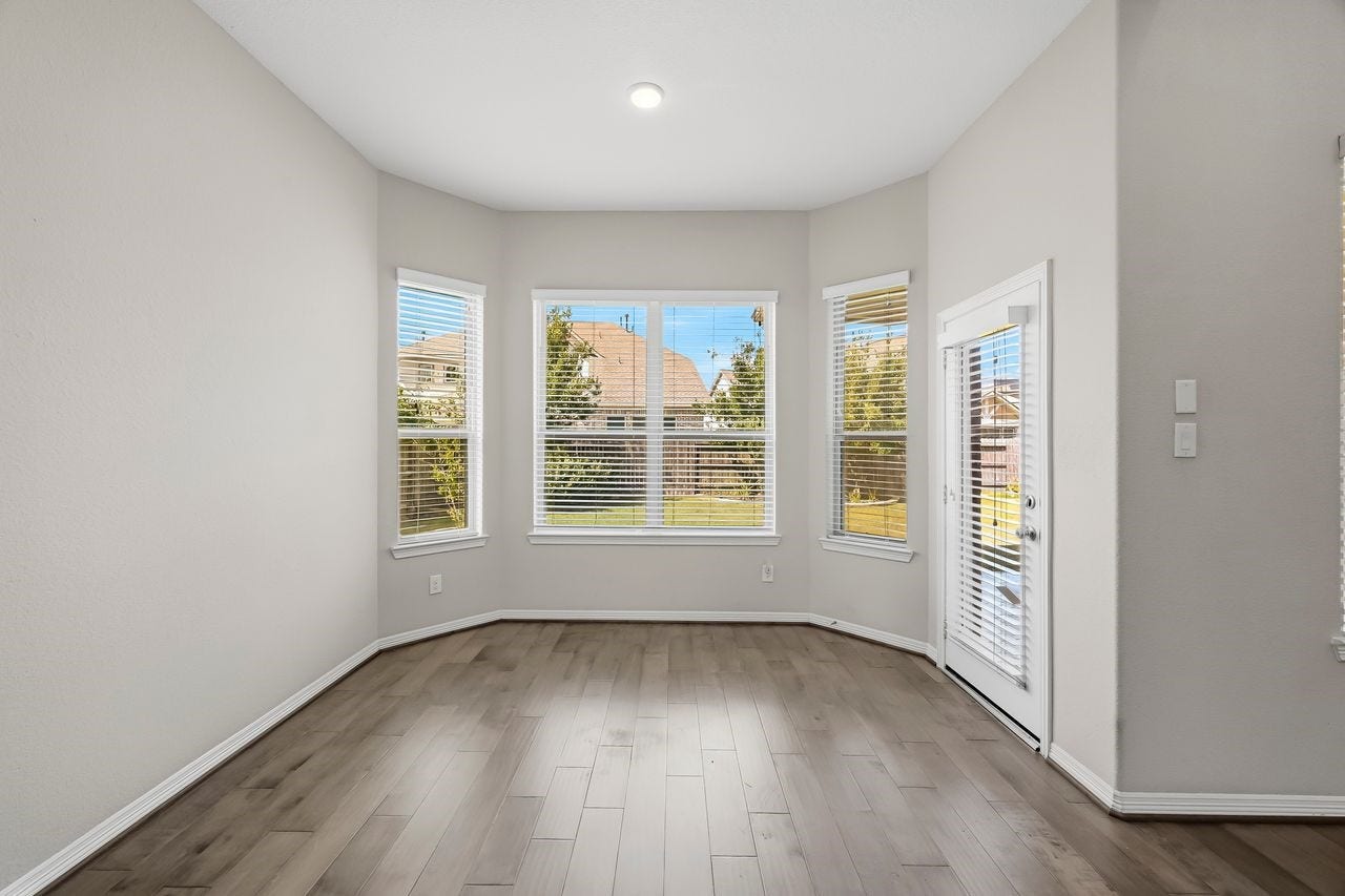 2215 Hermina Radler Drive, Richmond, TX 77469 Bathed in natural light, this elegant breakfast bay features rich wood flooring and offers a seamless visual connection to the manicured landscaping and covered patio just beyond the glass.