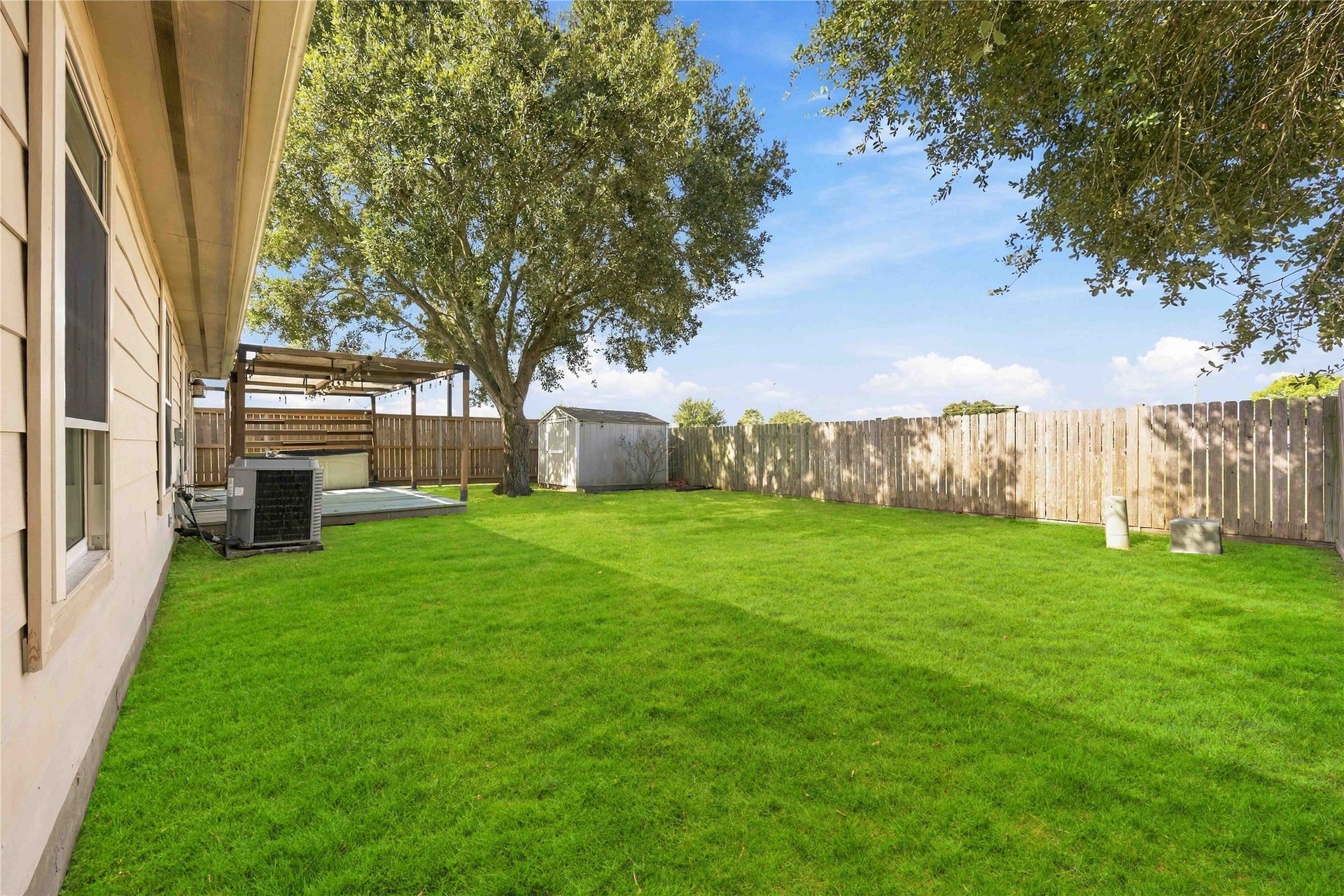 Fully fenced backyard offers an expansive lawn, mature shade tree, storage shed, and plenty of usable outdoor space.