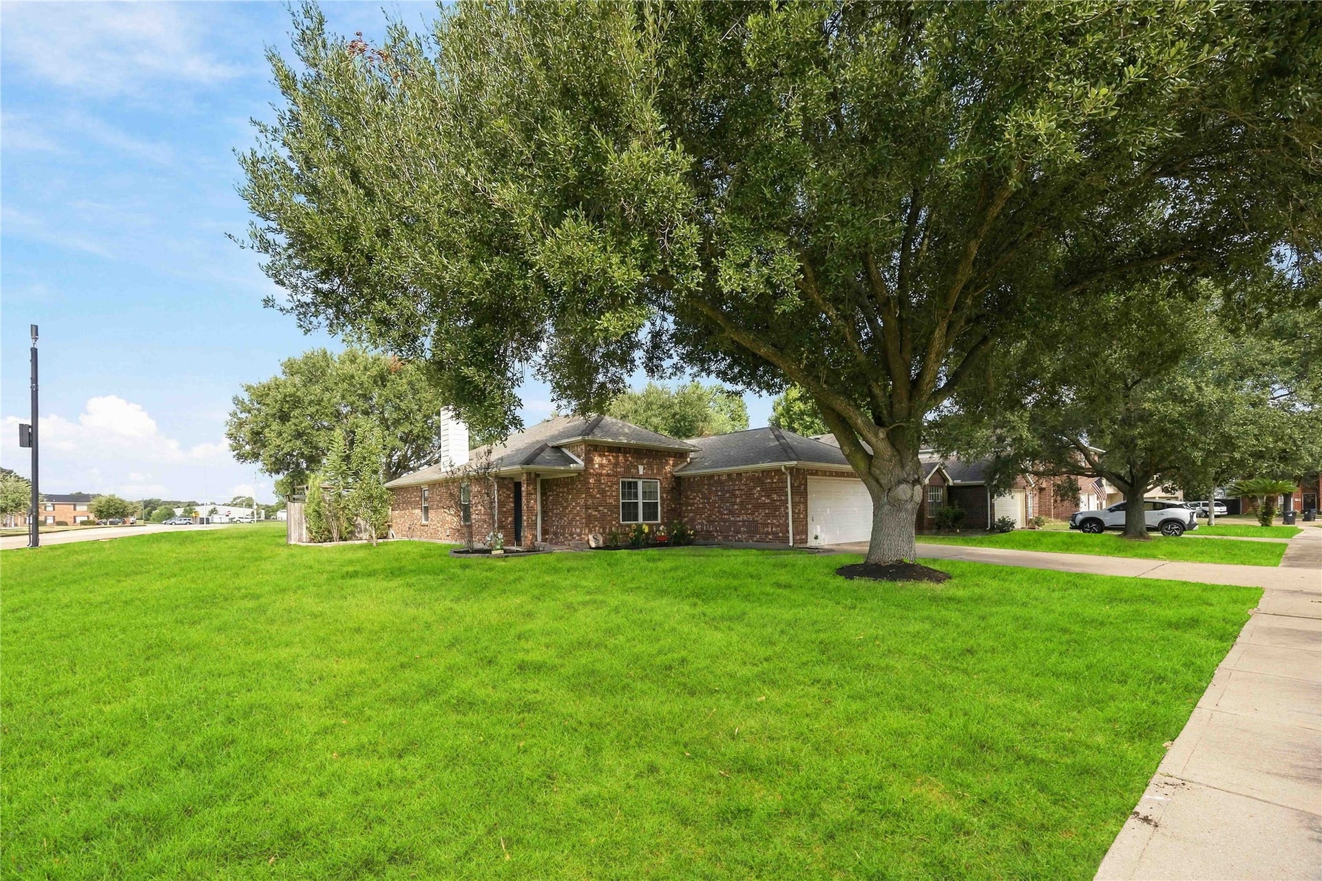 Generous corner-style lawn space with mature shade trees enhancing the homes curb appeal and outdoor setting.