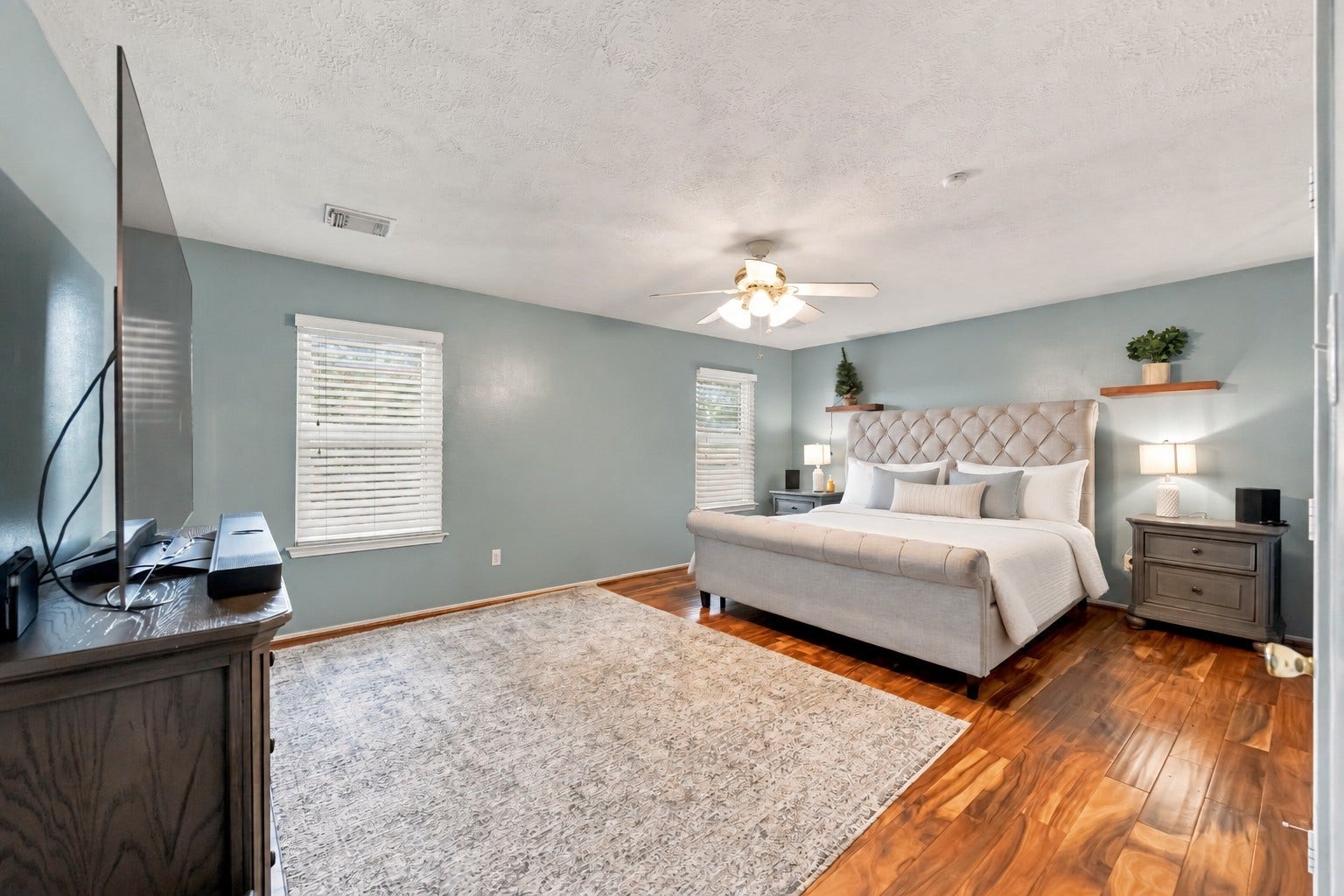 Expansive primary bedroom features abundant floor space, multiple windows, wood flooring, and direct access to the adjoining bath and closet areas.