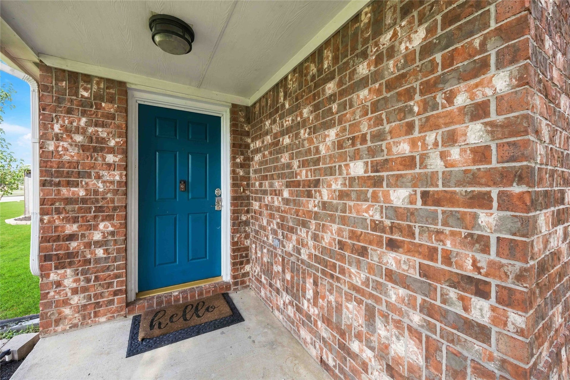 Covered front porch accented by a distinctive blue entry door and classic brick exterior.