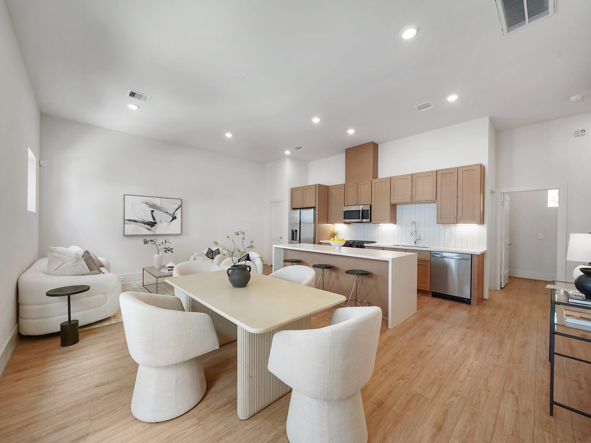 Experience contemporary elegance in this open-concept living space, featuring a sleek kitchen with stainless steel appliances and abundant cabinetry.
