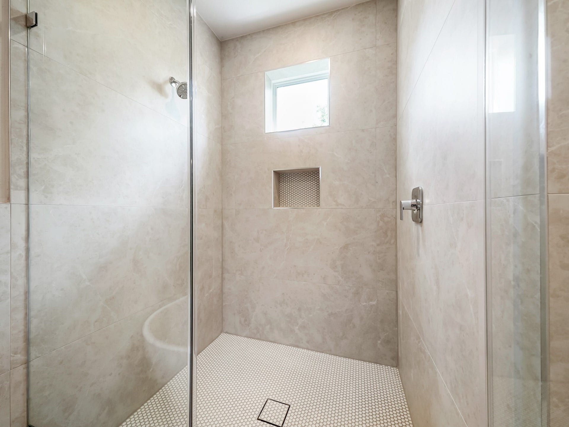 Experience luxury and space in this stunning walk-in shower, featuring sleek glass doors, elegant tile, and a modern niche for your essentials.