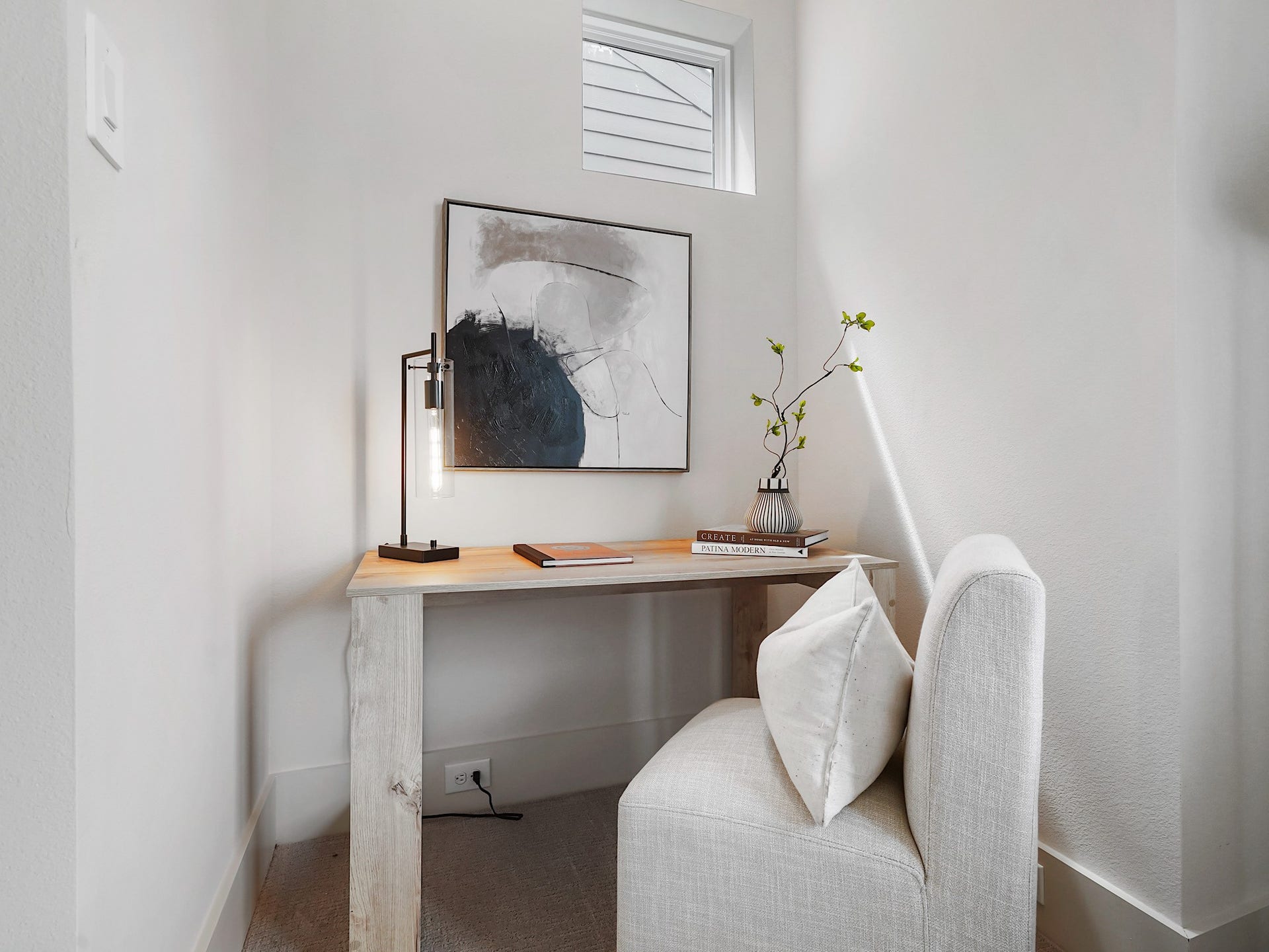 Discover a serene, light-filled nook in the primary bedroom, perfect for relaxing or reading, featuring a stylish desk and cozy chair for ultimate comfort.