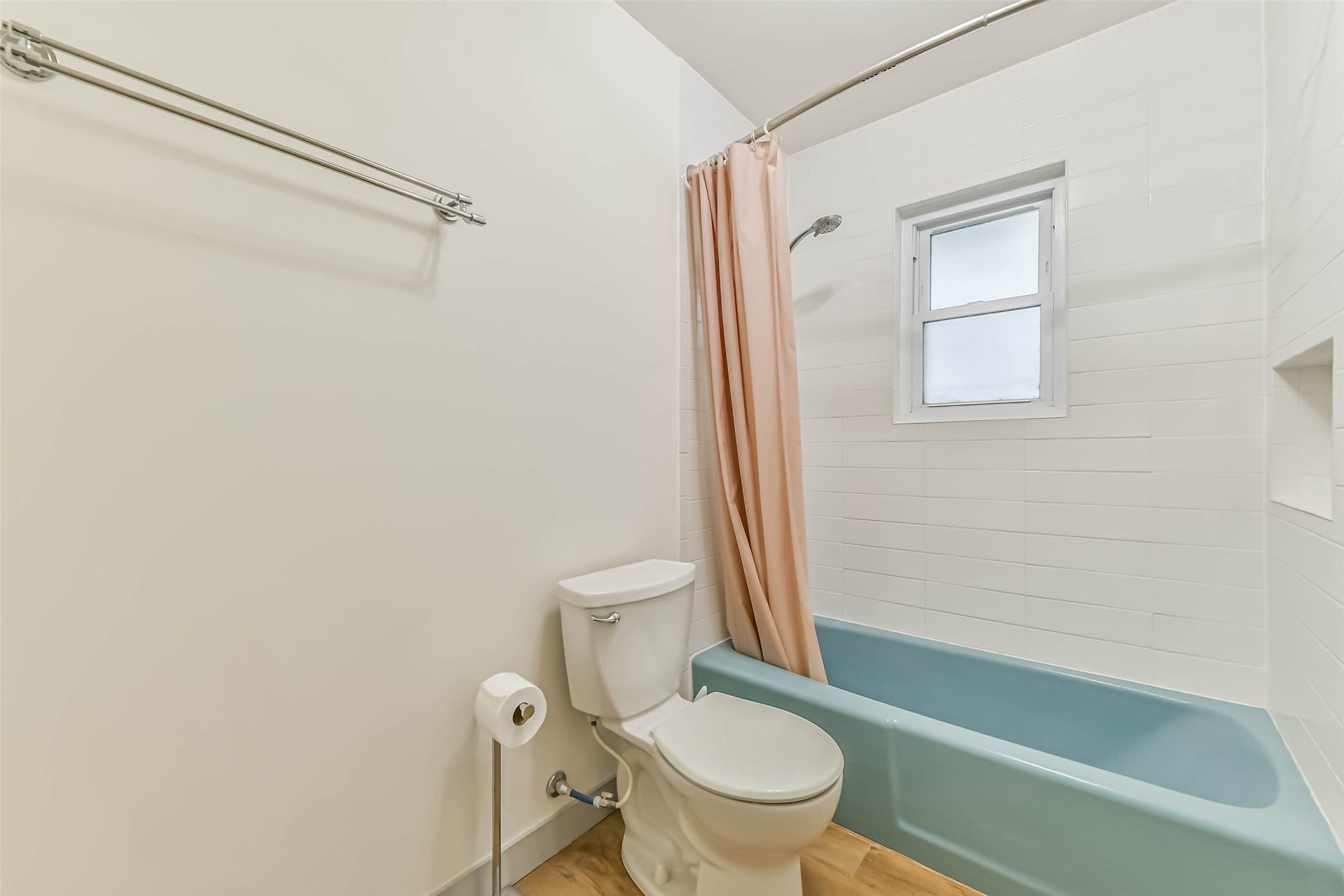 Bathroom features a light blue bathtub with a shower, complemented by white tiled walls.