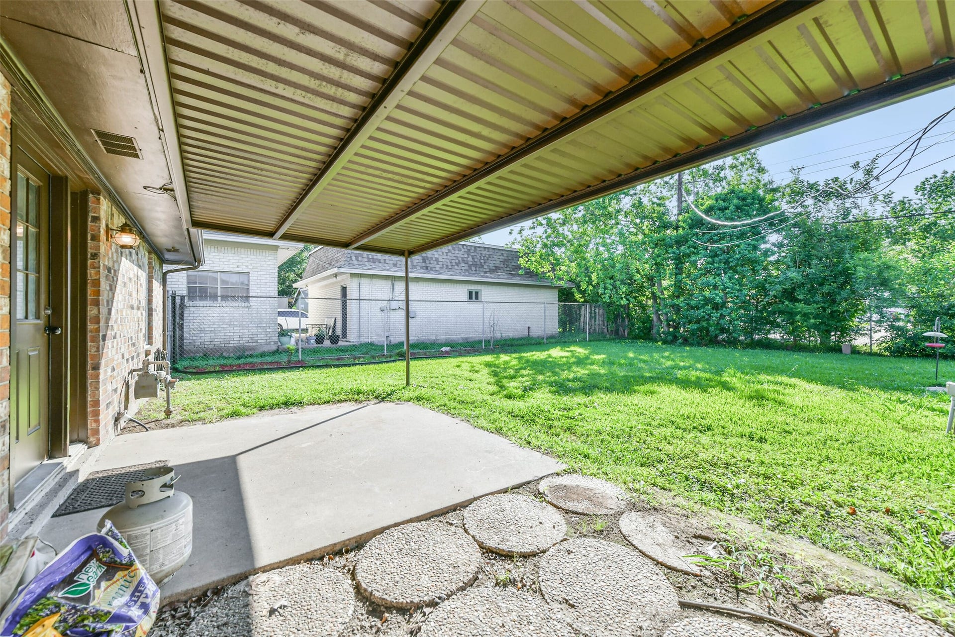 Backyard with a spacious covered patio, perfect for outdoor relaxation. The yard is grassy and fenced, providing privacy and space for gardening or play.