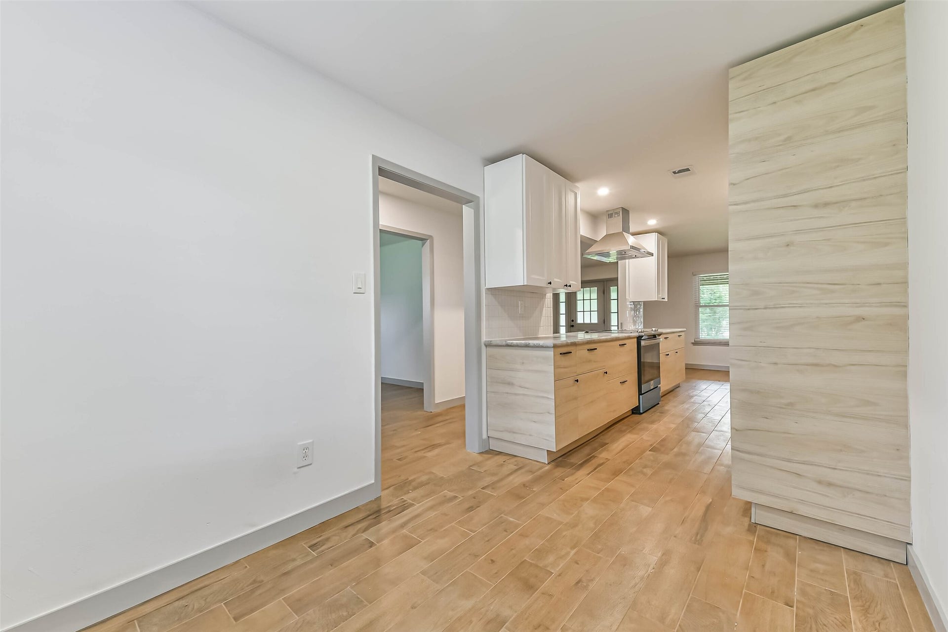 Modern kitchen with light wood cabinetry, stainless steel appliances, and a spacious layout.