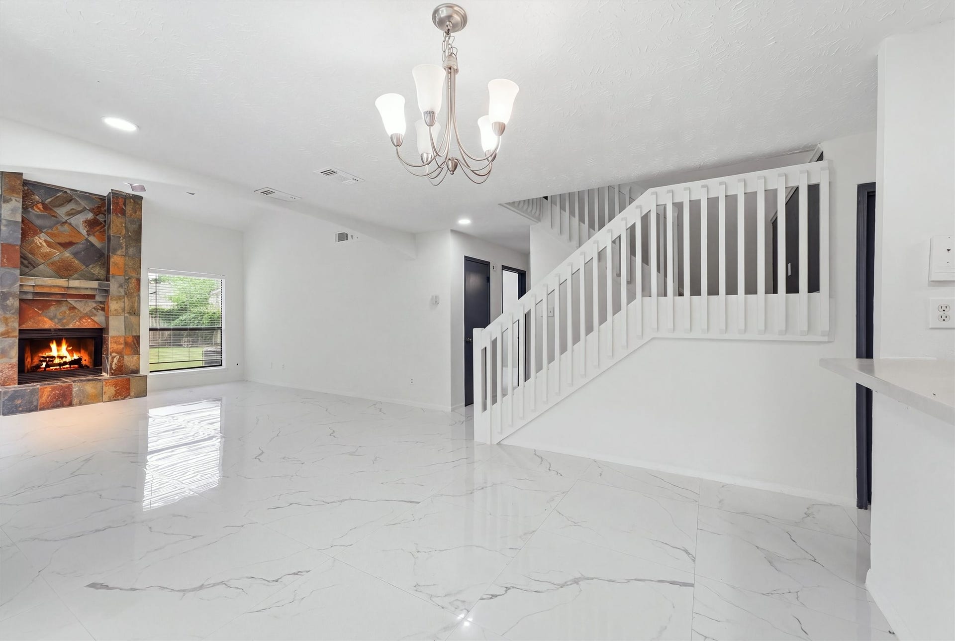 12719 Hollandale Drive, Houston, TX 77082 Dining area sits beside the kitchen beneath a chandelier, surrounded by three windows and glossy marble-look tile flooring.