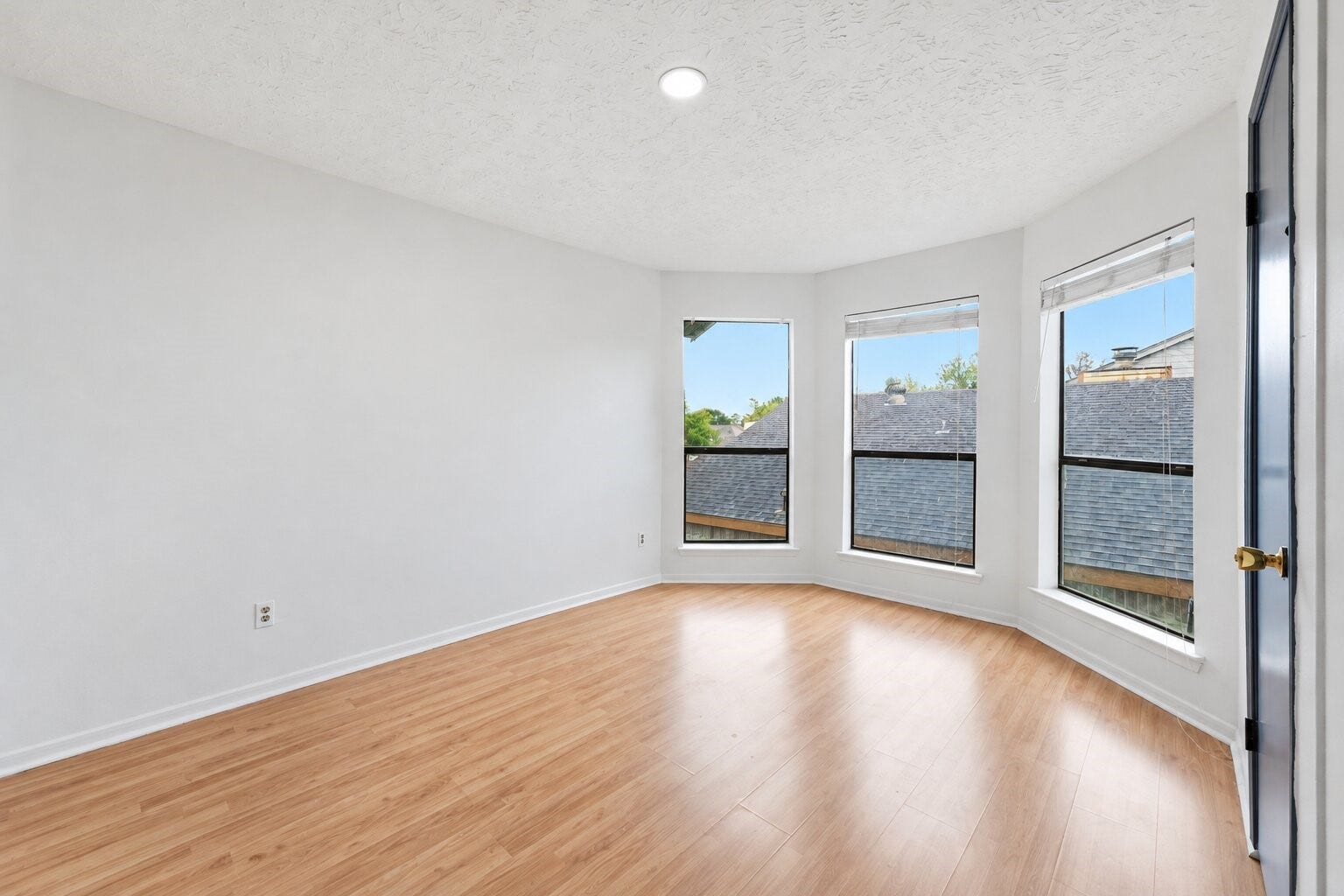 12719 Hollandale Drive, Houston, TX 77082 Secondary bedroom welcomes daylight through three angled windows, complemented by wood-look flooring and a flexible layout