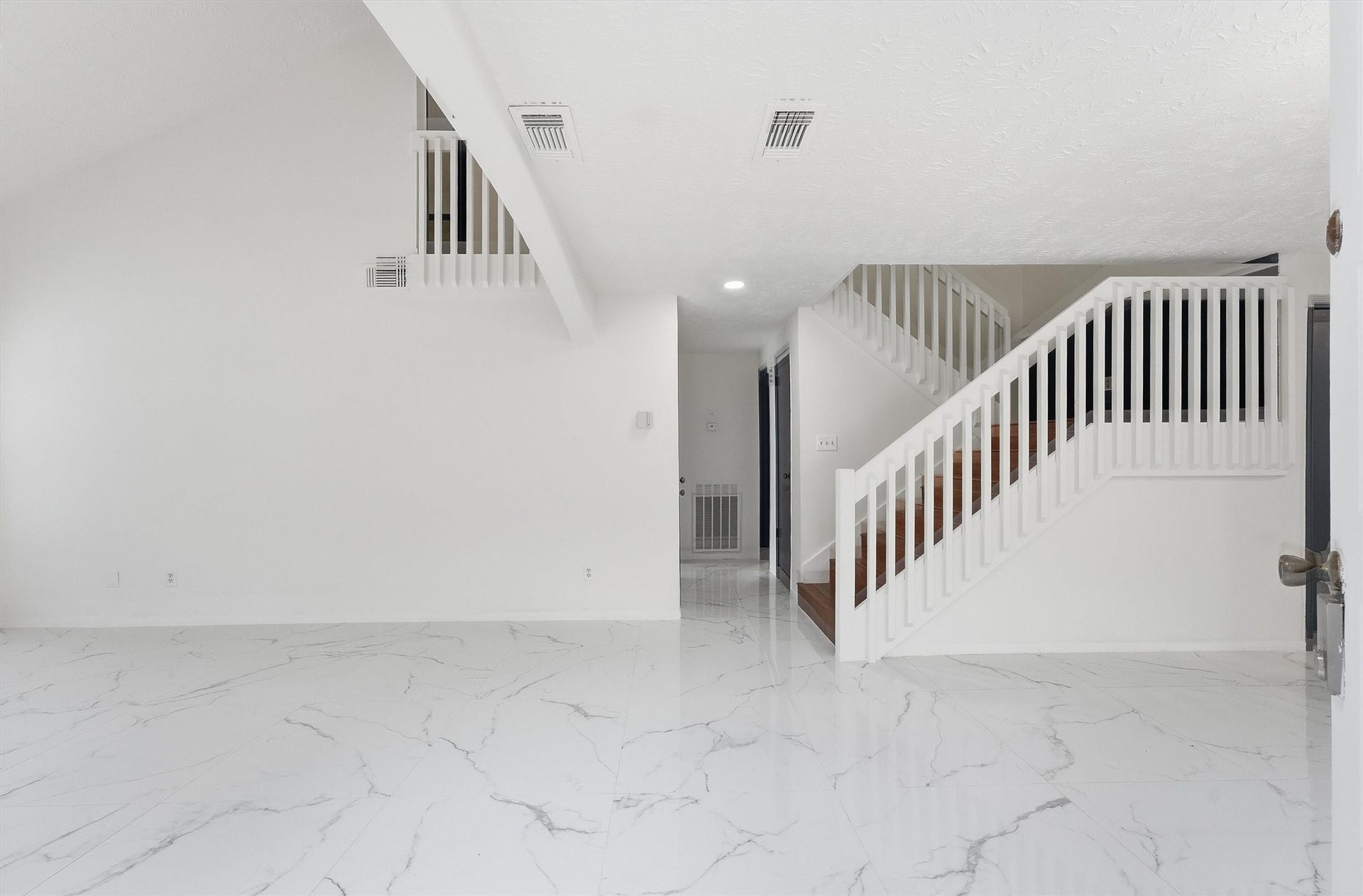 12719 Hollandale Drive, Houston, TX 77082 Entryway opens to glossy marble-look tile flooring and a staircase with white railings leading to the upper level.