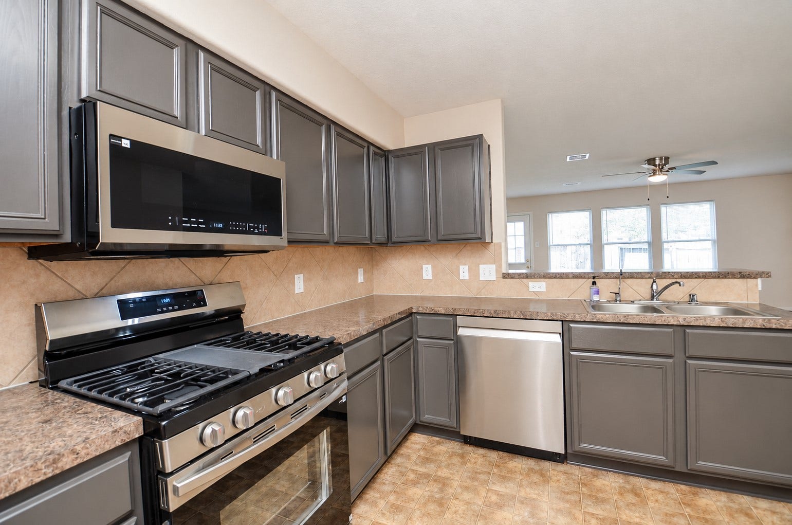 5031 Grove Square Court, Katy, TX 77449 Closer view of the kitchen showcasing the stainless steel gas range, built-in microwave, dishwasher and attractive gray cabinetry.