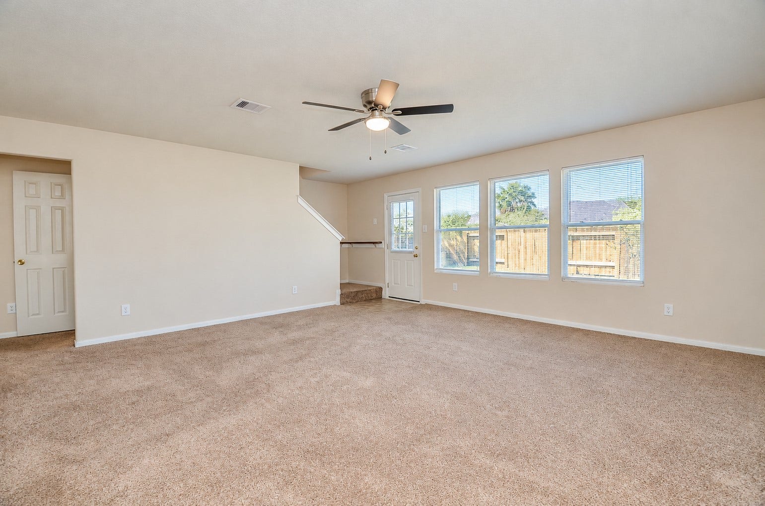 5031 Grove Square Court, Katy, TX 77449 Spacious family room featuring a ceiling fan, neutral carpeting and abundant natural light from multiple windows.