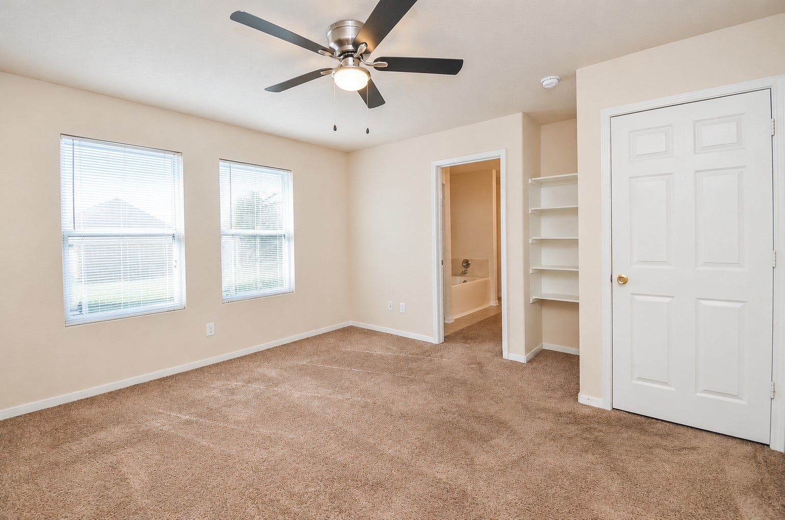 5031 Grove Square Court, Katy, TX 77449 Spacious first-floor primary bedroom with two windows, a ceiling fan and convenient access to the private bathroom and walk-in closet.