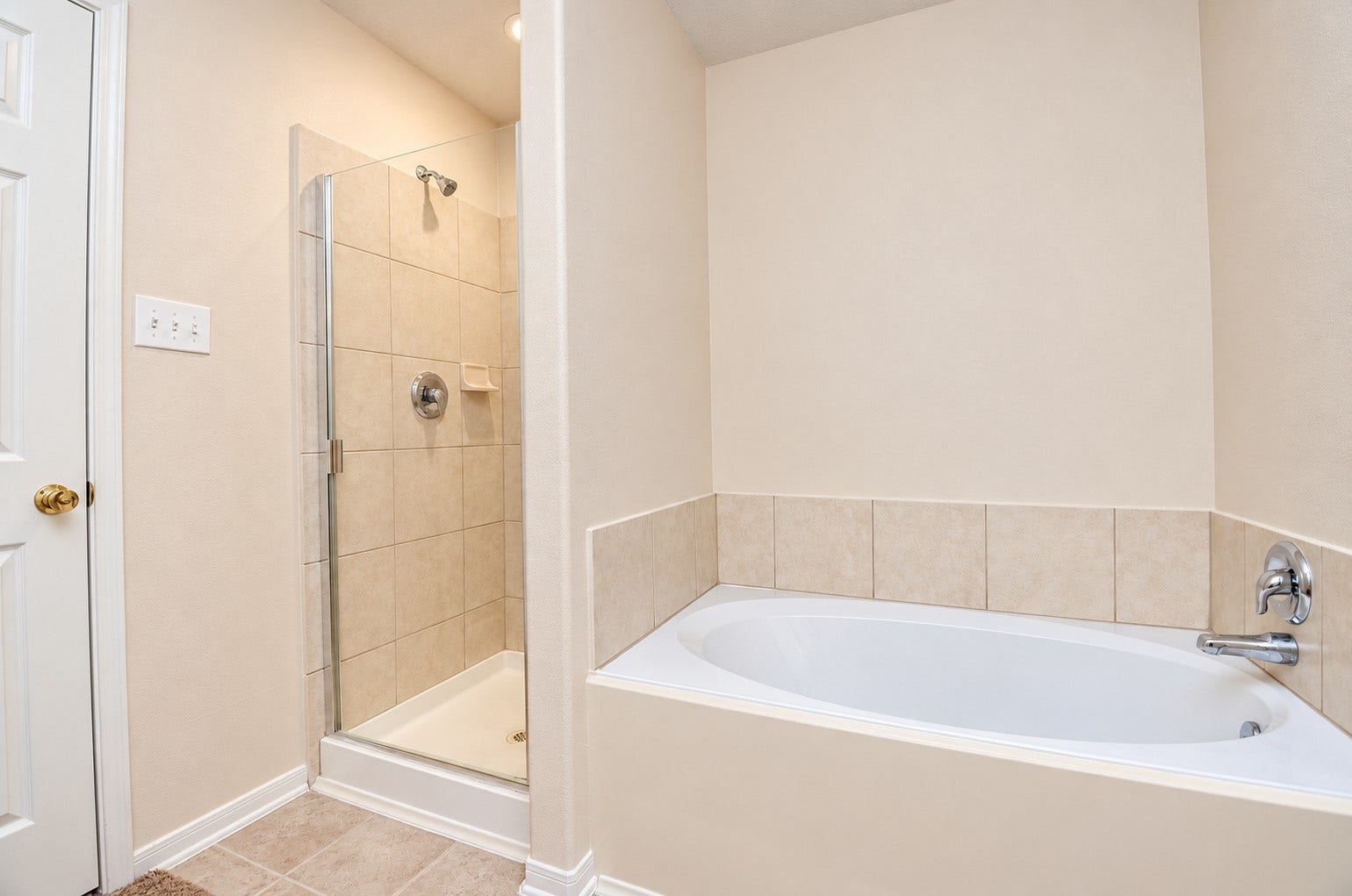 5031 Grove Square Court, Katy, TX 77449 First-floor primary bathroom featuring a soaking tub, separate glass-enclosed shower and neutral tile finishes.