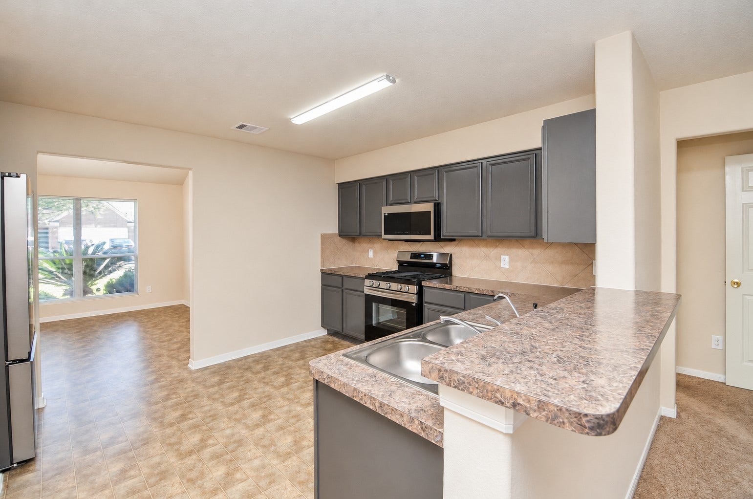5031 Grove Square Court, Katy, TX 77449 Kitchen featuring generous counter space, ample cabinetry, a breakfast bar and convenient access to the formal dining room.