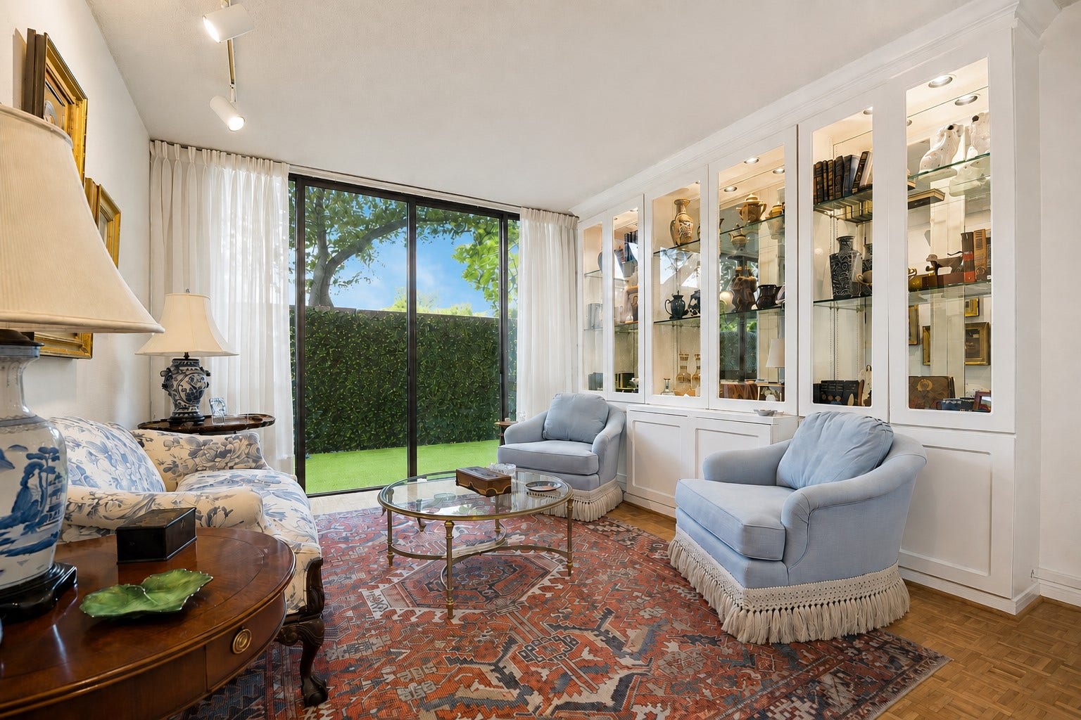 Secondary guest bedroom with a closet. Currently being used as additional living space. Showcasing elegant custom built-ins with Lit display shelves and glass paneled cabinetry.