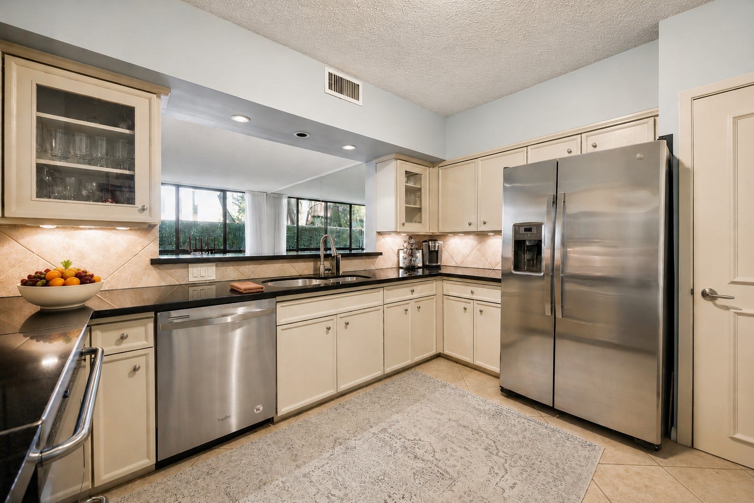 Alternate kitchen view featuring stainless steel appliances, sweeping counter space and abundant custom cabinetry