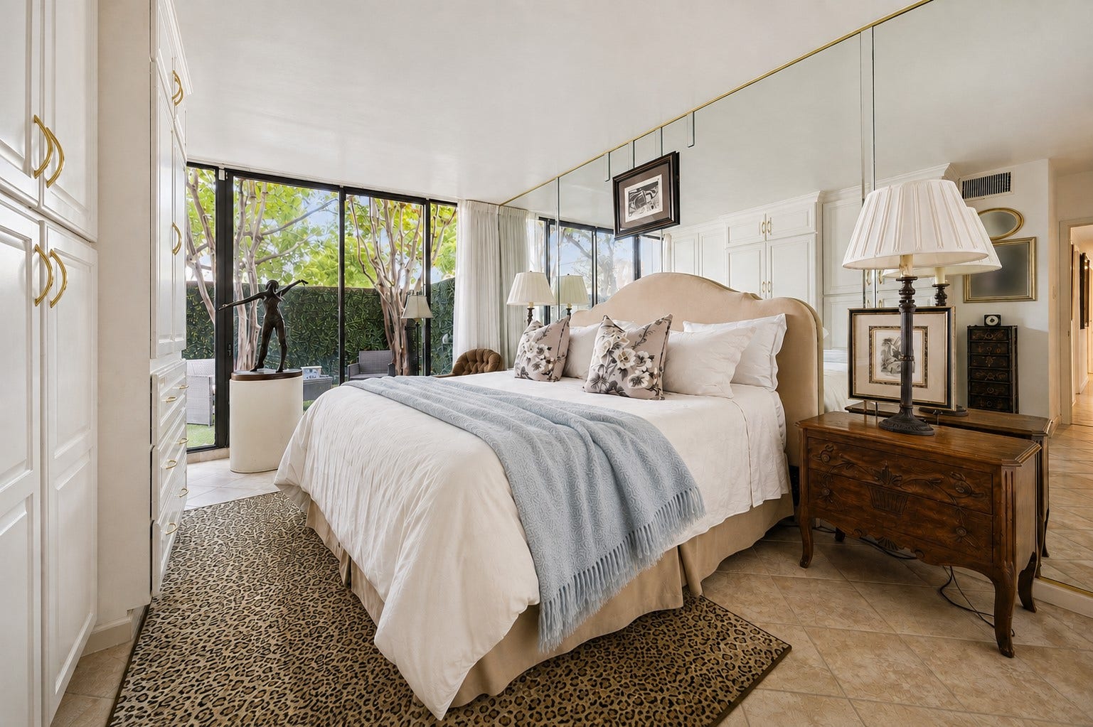 Enjoy quiet moments in your primary bedroom. A glass sliding door with private secluded terrace access, enhanced by a striking mirrored accent wall, a tailored built-in storage and a large walk-in dressing area