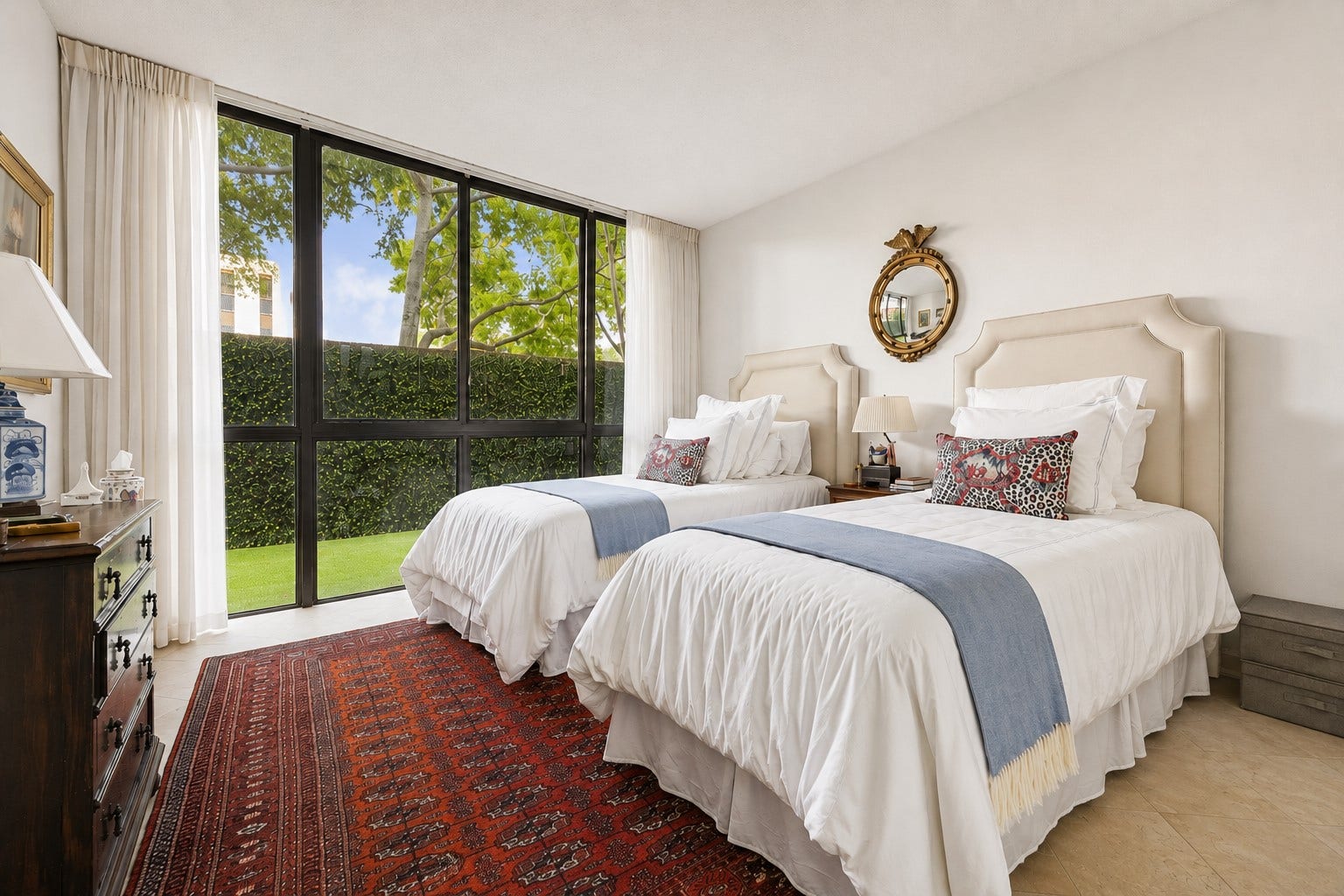 A well proportioned spacious second guest bedroom with wall of windows overlooking the outdoor terrace