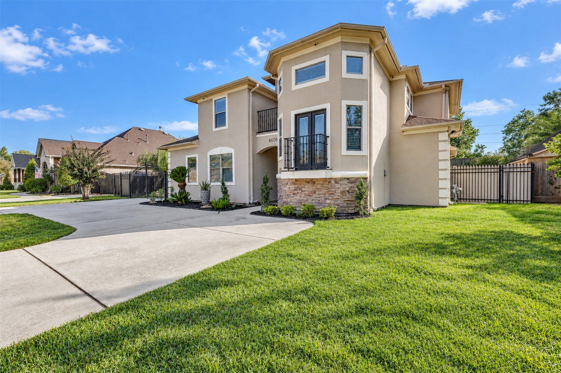 8606 Argentina Street, Houston, TX 77040 Front Exterior: Distinctive two-story architecture with an elegant stucco faade, stone accents, and two balconies that create striking curb appeal.