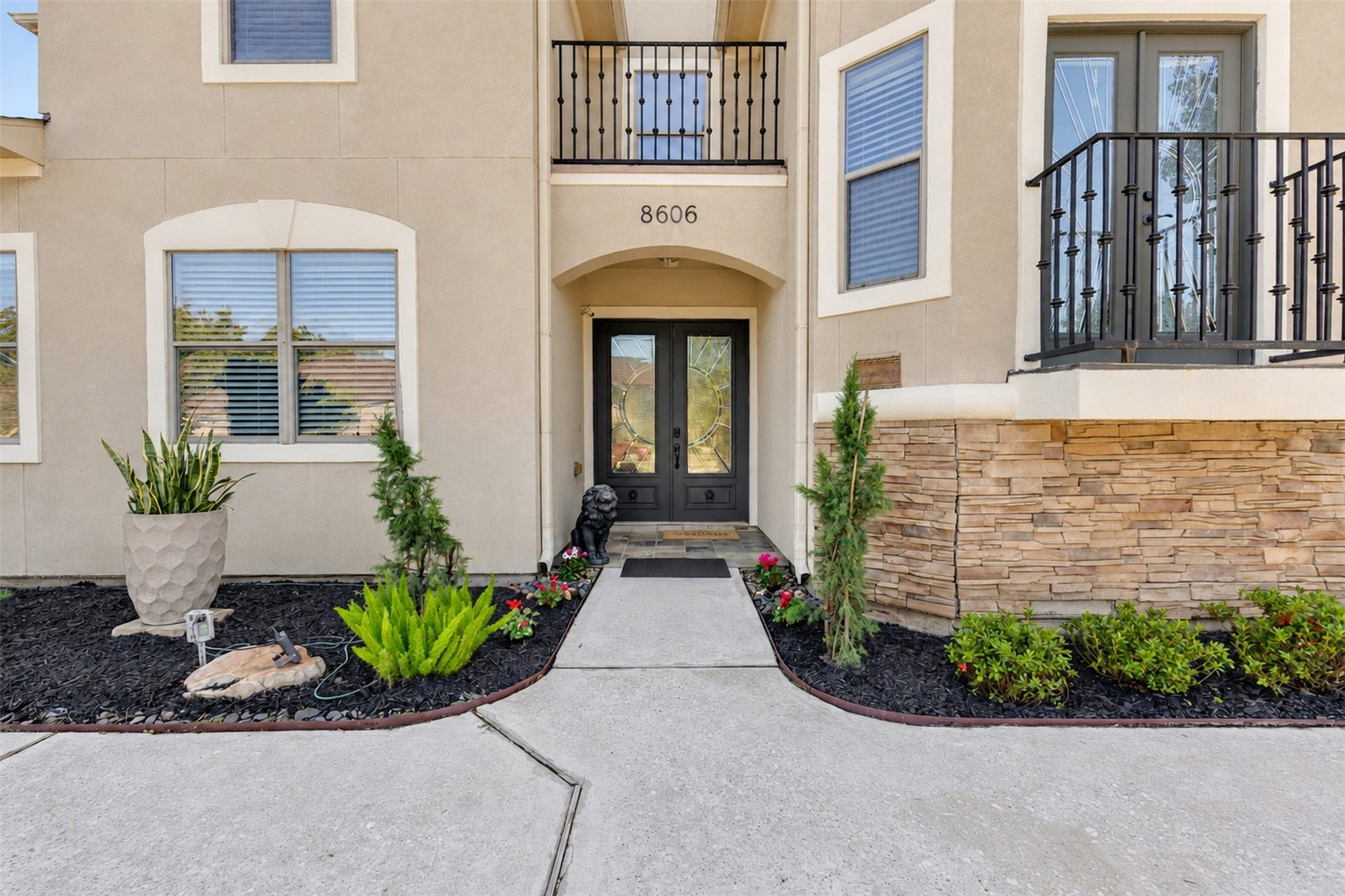 8606 Argentina Street, Houston, TX 77040 Front Exterior: Distinctive two-story architecture with an elegant stucco faade, stone accents, and two balconies that create striking curb appeal.